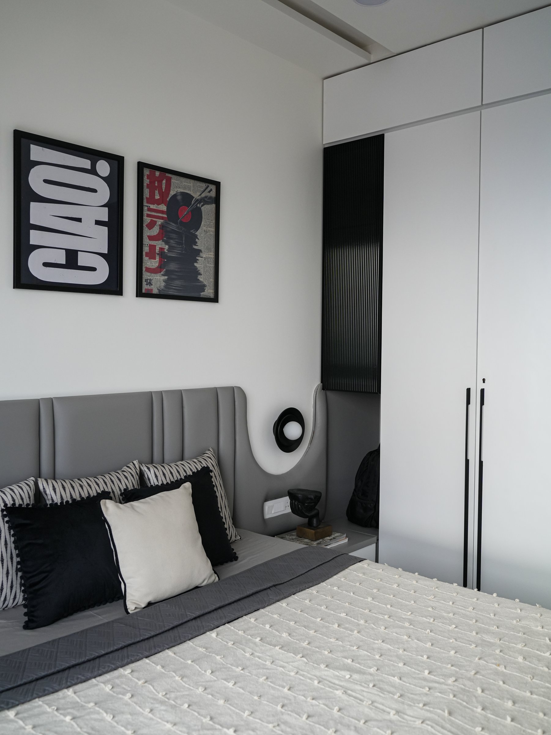 A curved wall detail with a small sconce and niche shelf eases the transition to the full-height wardrobe