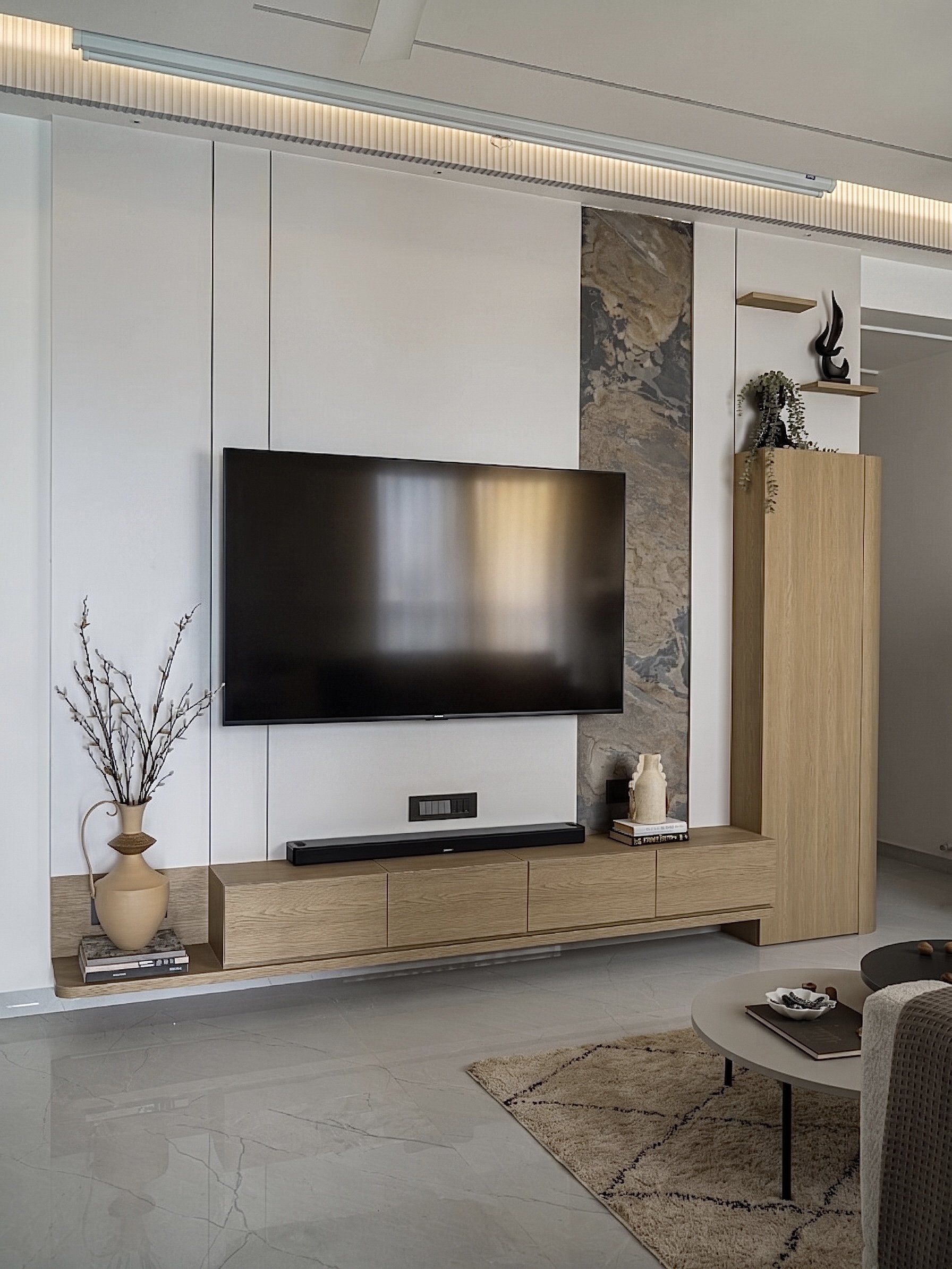 The media wall, treated as integrated joinery with a floating light-toned console and a single vertical inlay of stone veneer
