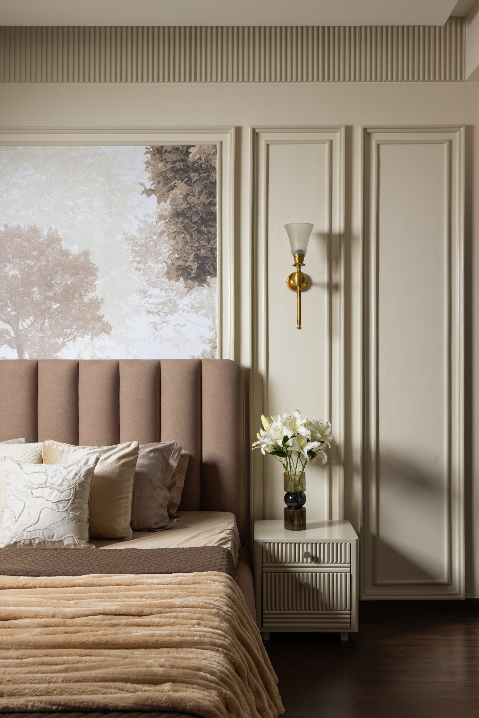 The master bedroom, where a channel-tufted headboard rests against a misty forest mural