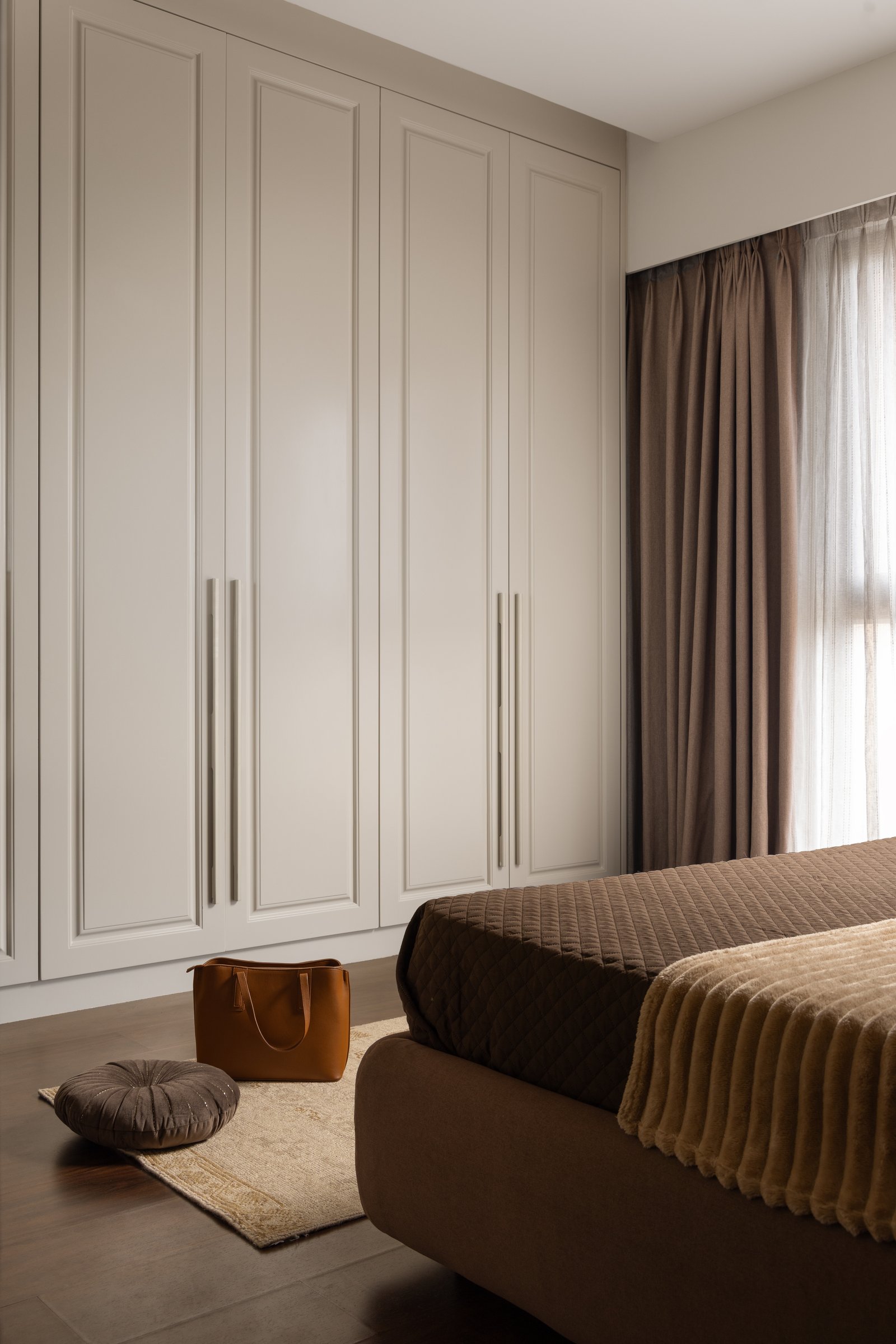 Full-height cream cabinetry opposite the bed, absorbing storage into the architecture