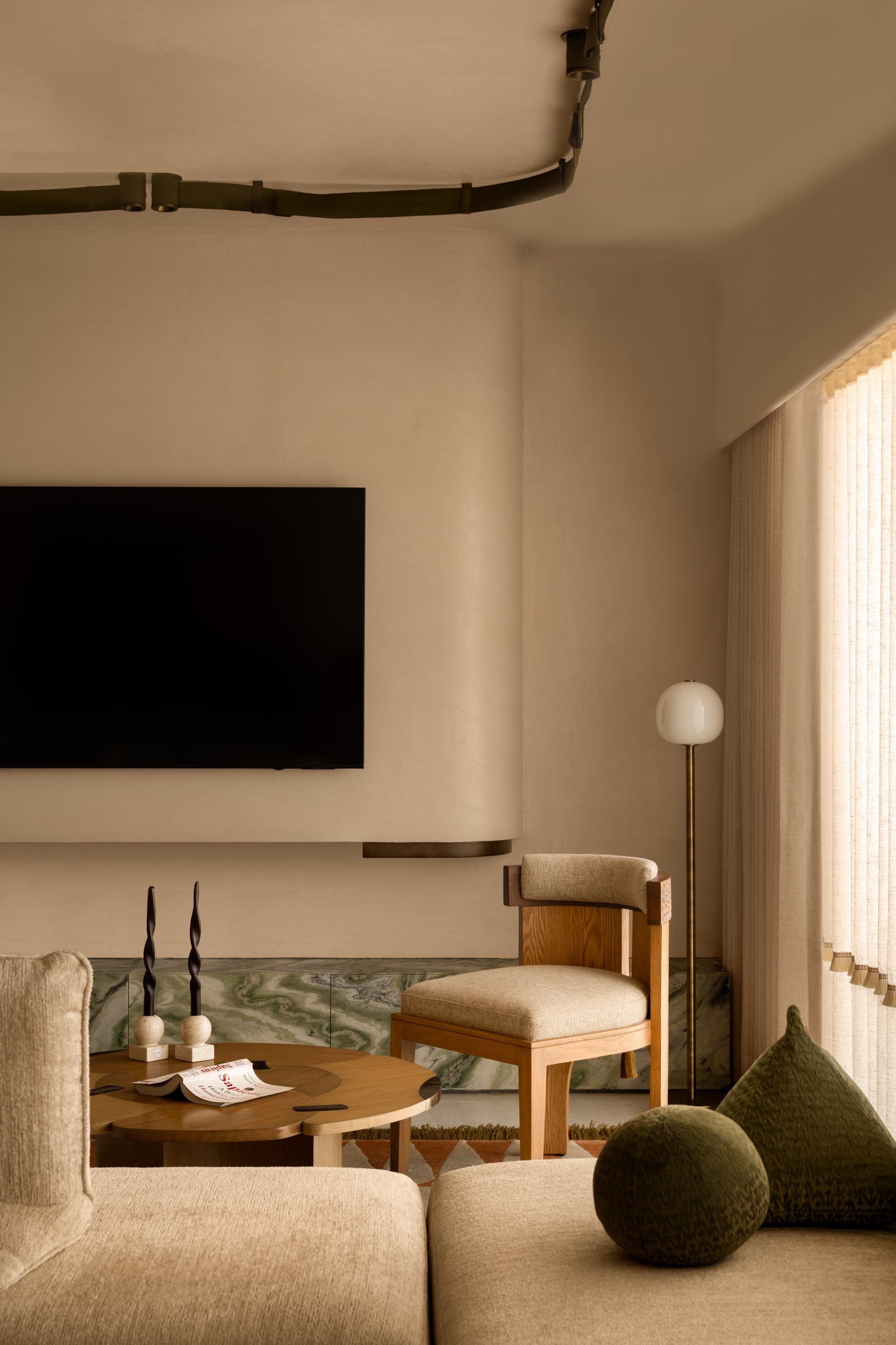 The media wall, where a green stone console grounds the composition and a globe floor lamp mediates between architectural gesture and furniture