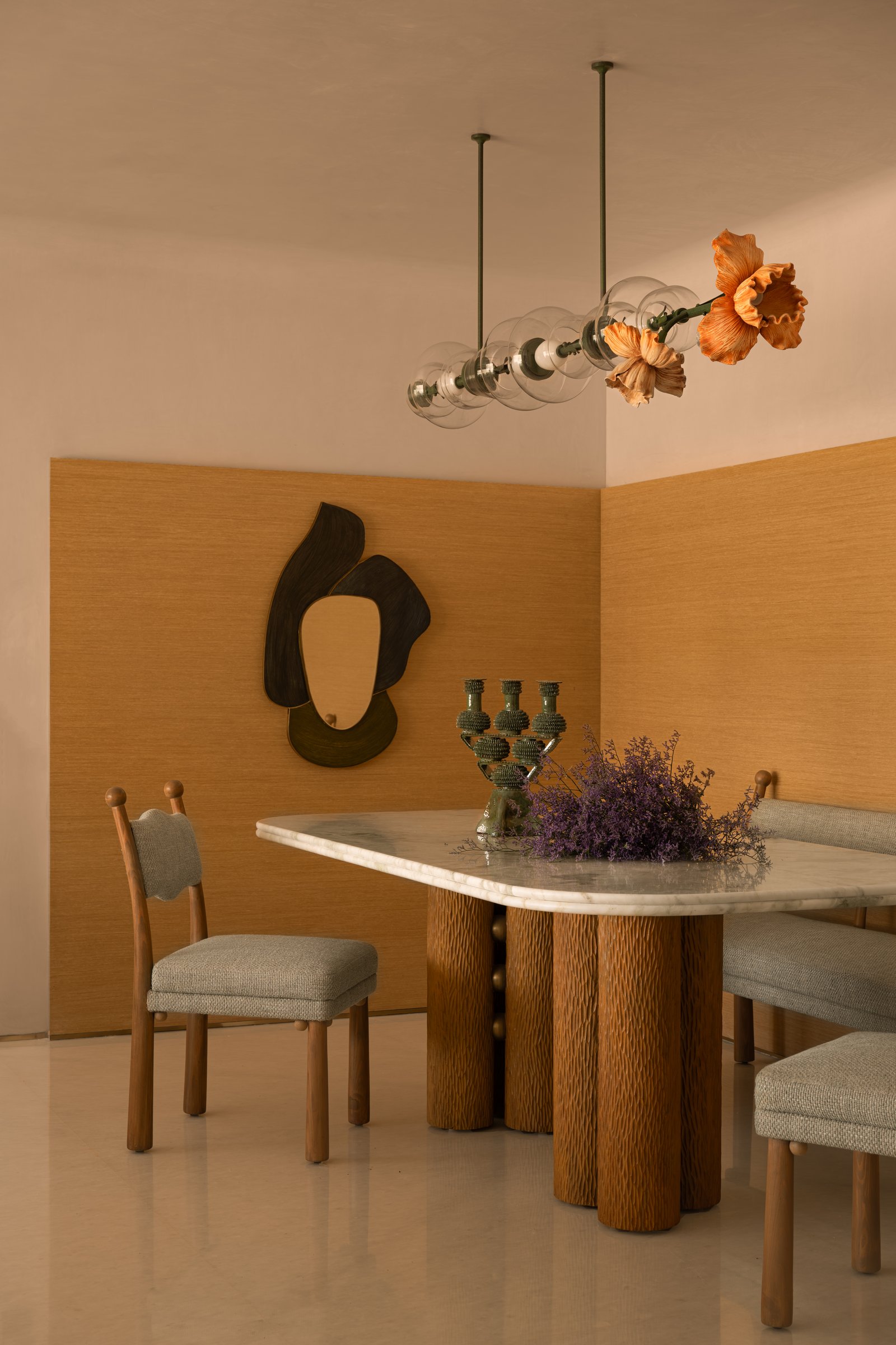 A detail of the dining vignette, where a sculptural mirror and ceramic candelabra continue the room's quiet dialogue between craft and colour