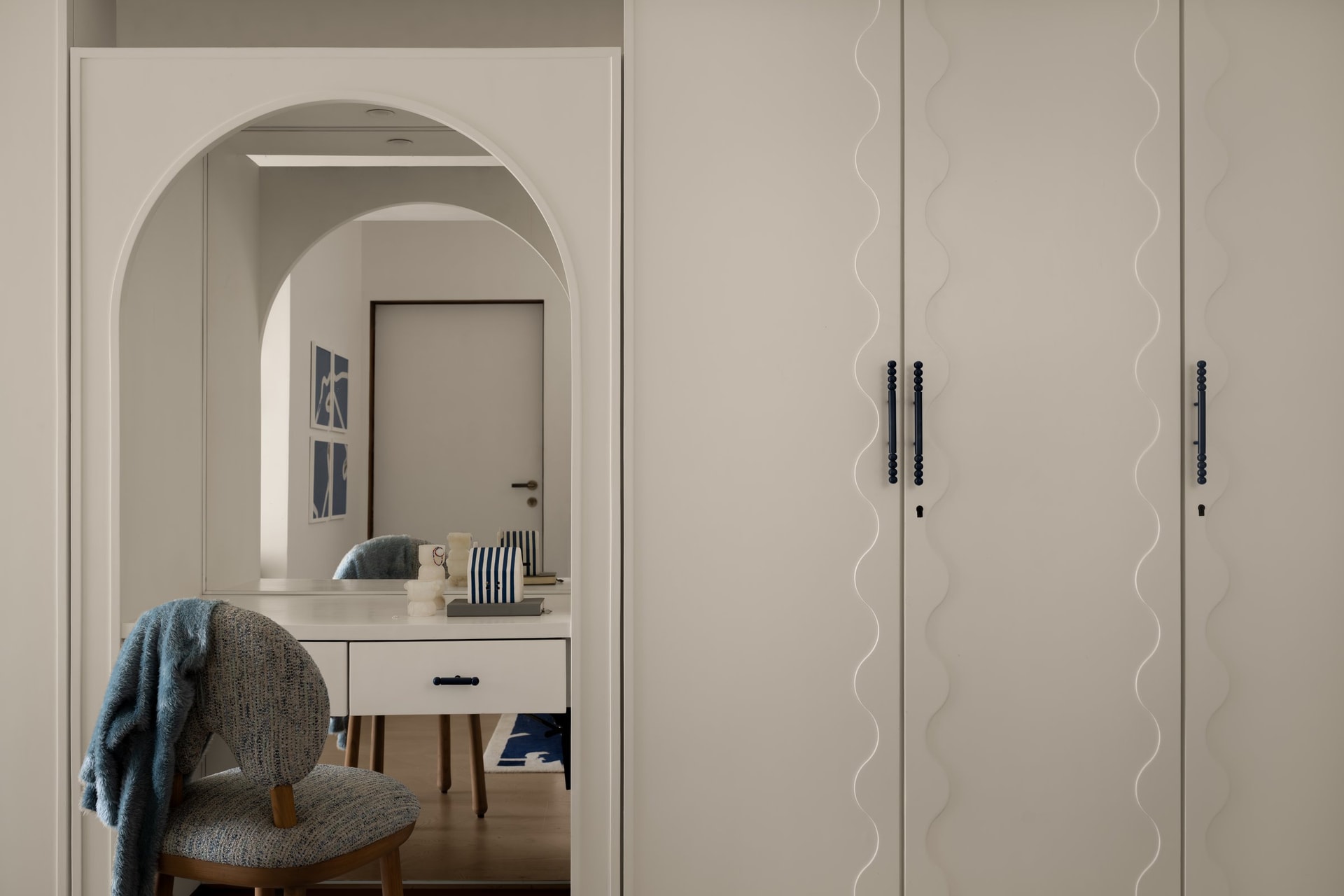 The dressing arch, where a curved opening leads through to a compact vanity zone tucked between the wardrobes