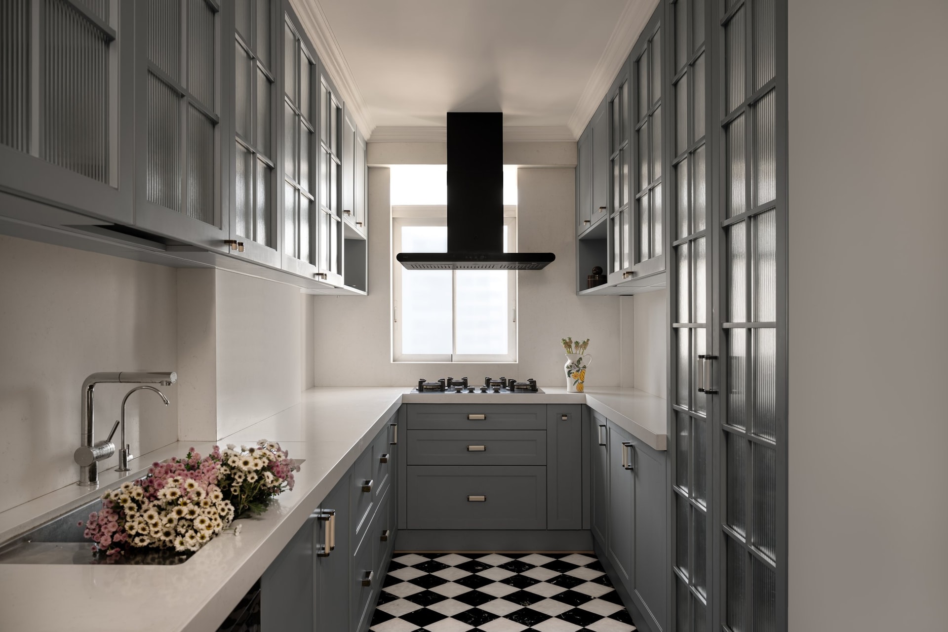 The galley kitchen, where slate-grey Shaker cabinetry and a black-and-white chequered floor introduce a more classical register