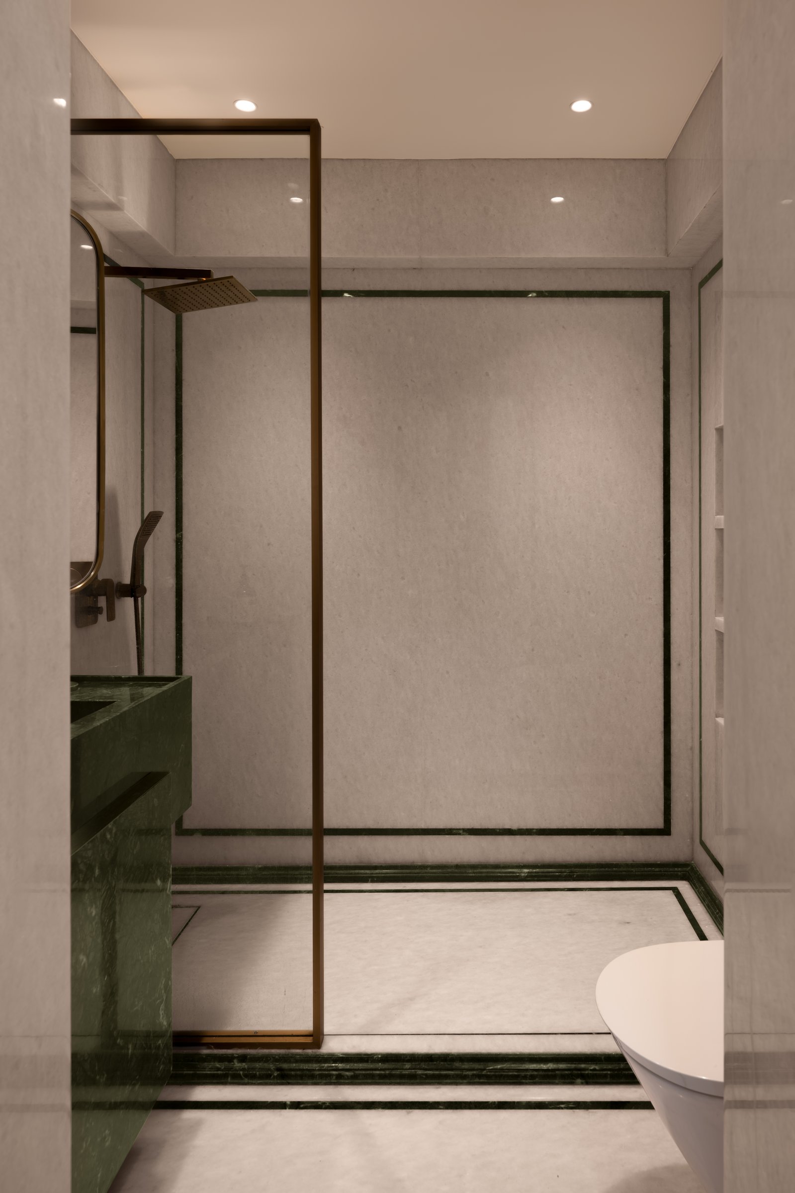 The master bathroom, where cream stone and green stone banding create a quiet architectural drawing on the walls