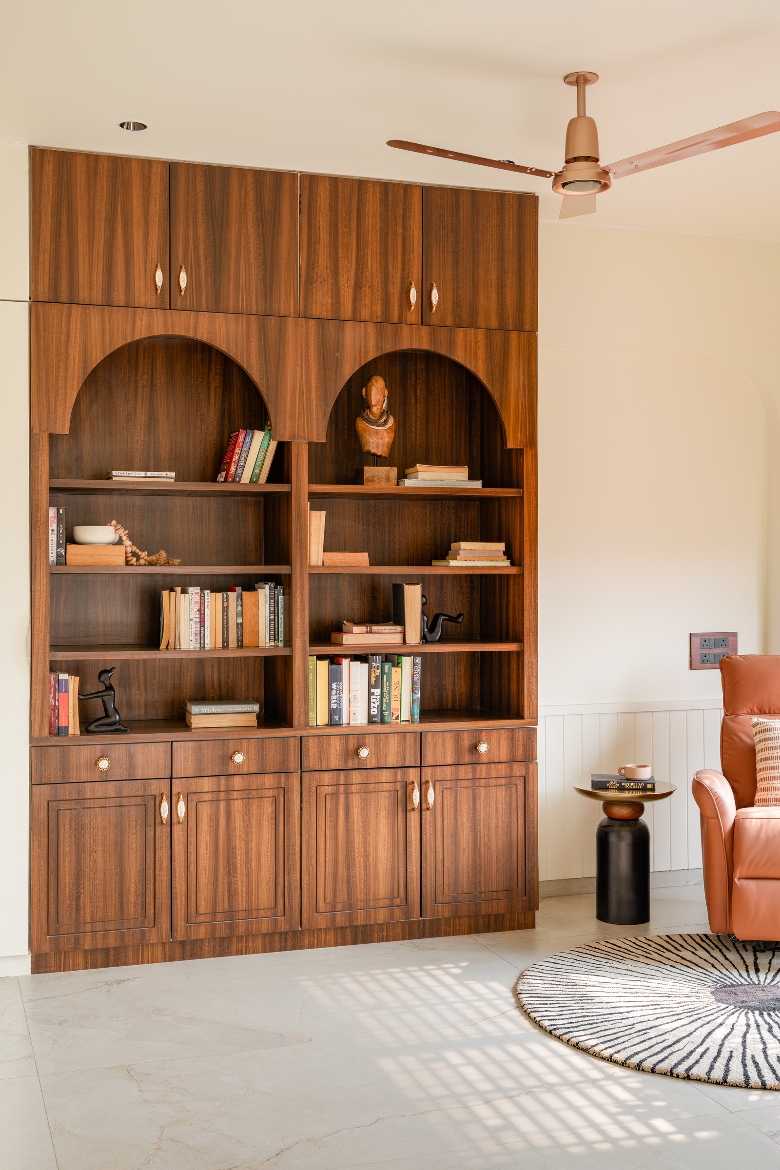 The family lounge, where a hardwood library wall in warm tones sits beside a tan leather recliner and a striped round rug