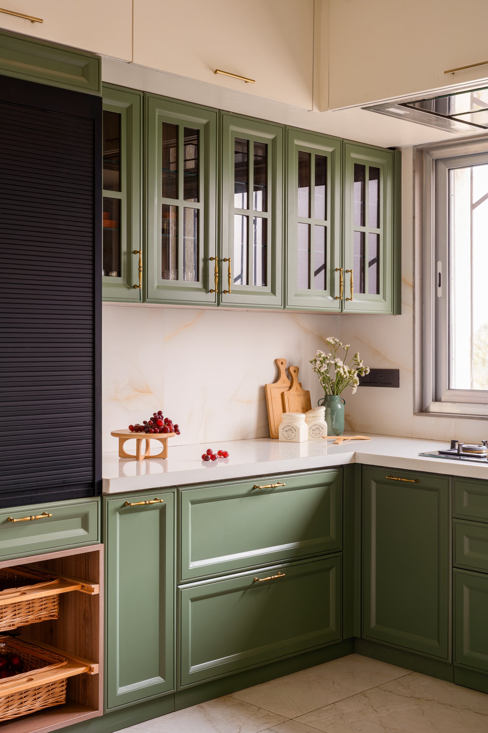 The kitchen, where sage cabinetry with brass pulls meets a veined stone backsplash