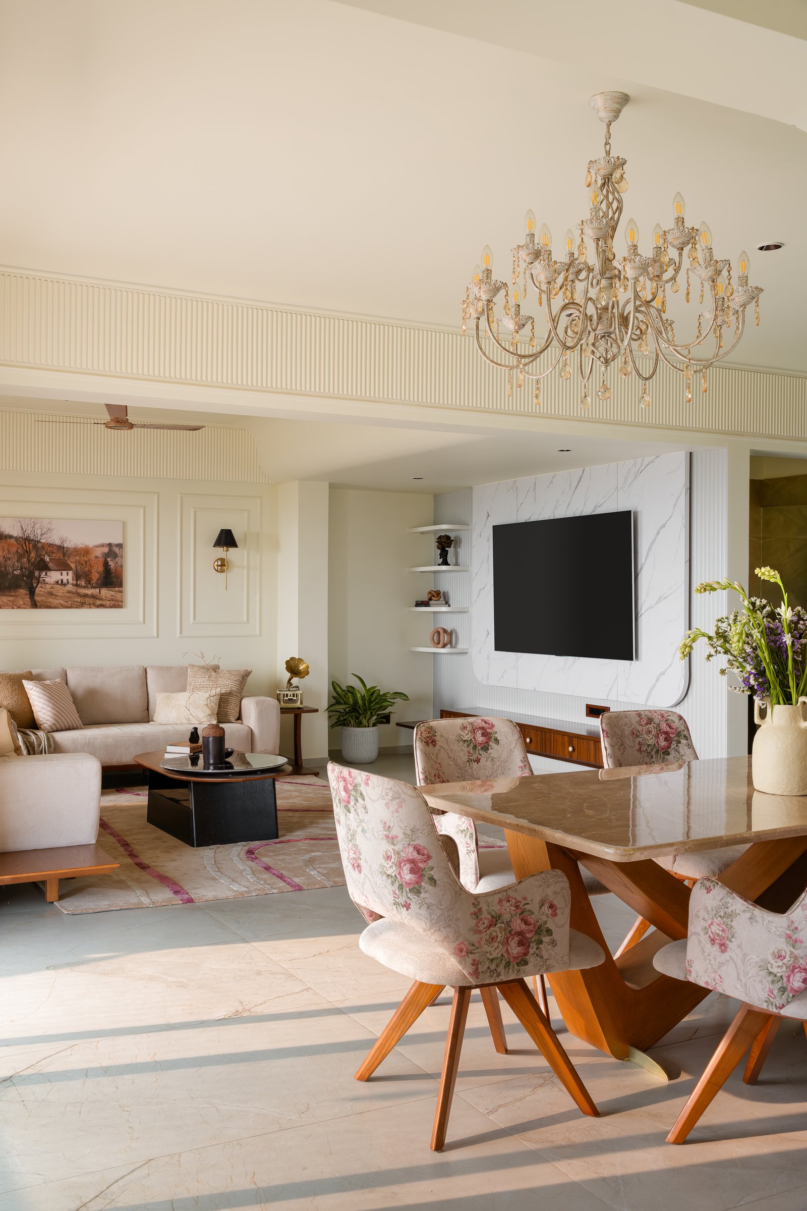 The living and dining rooms, where a moulded shell holds a floral-upholstered dining set and a soft neutral seating group in continuous sequence