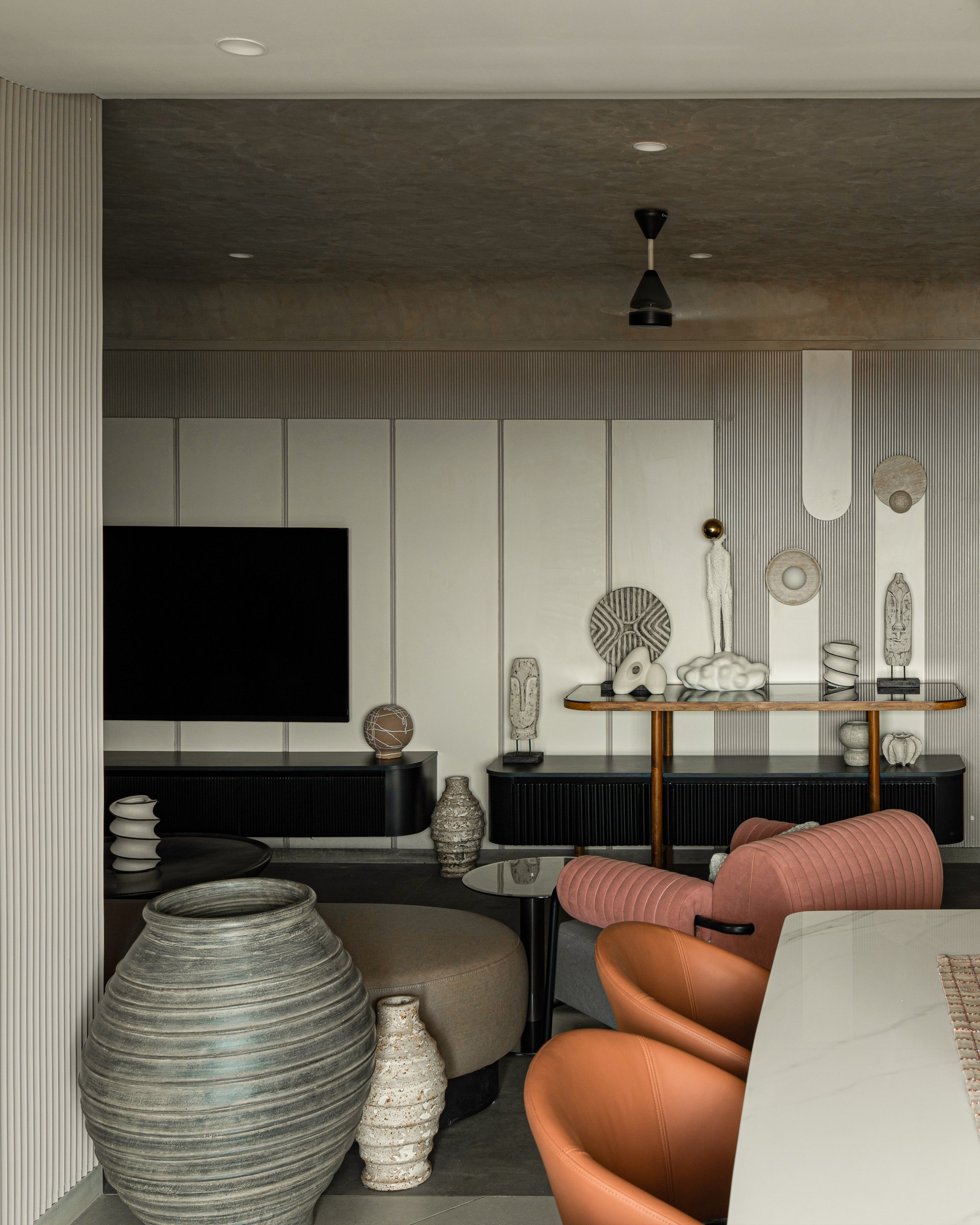 The media wall, where fluted black joinery becomes a shelf for the family's collection of small sculptural objects