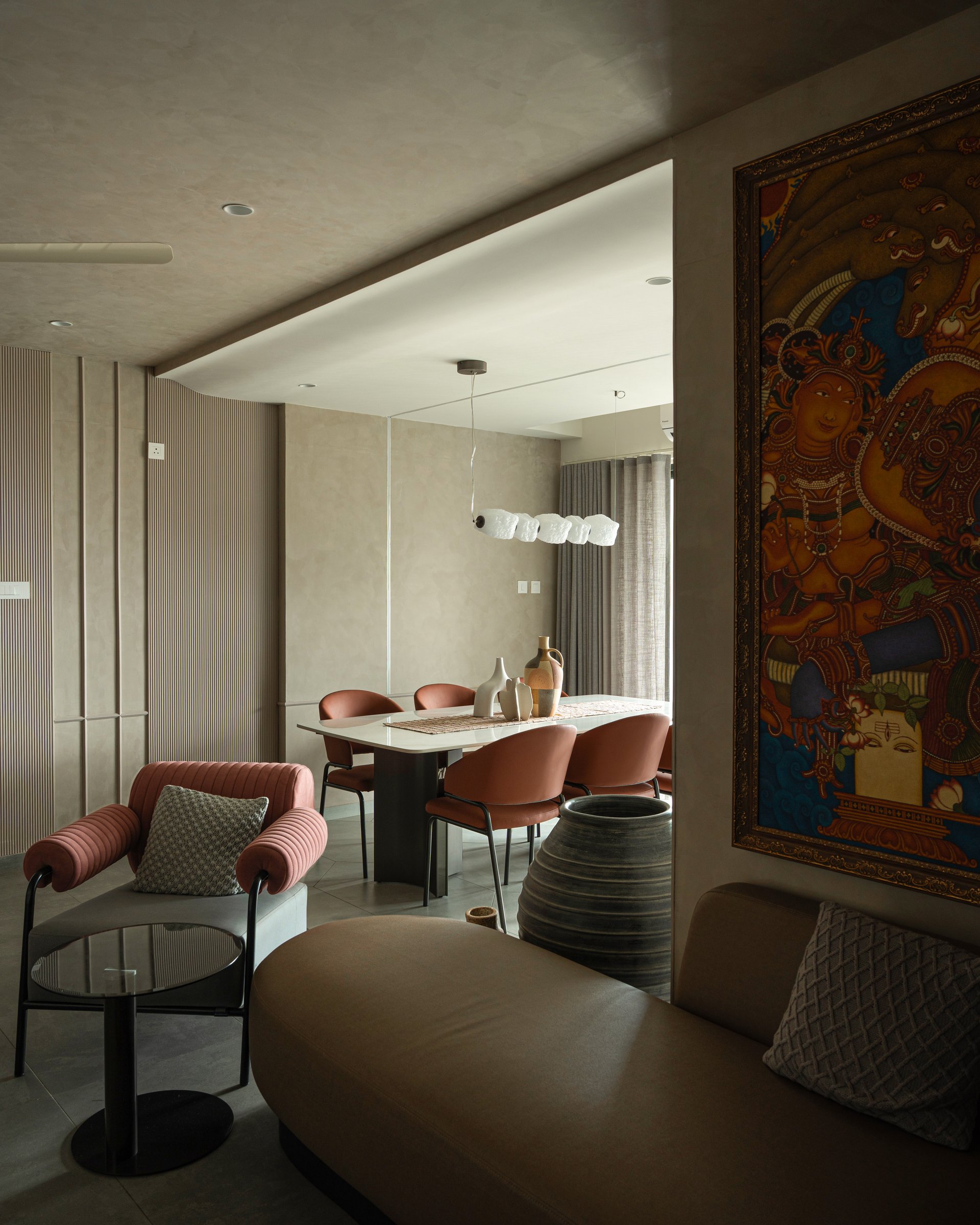 In the dining area, a sculptural pendant of clustered white forms hangs above a stone-topped table paired with terracotta upholstered chairs
