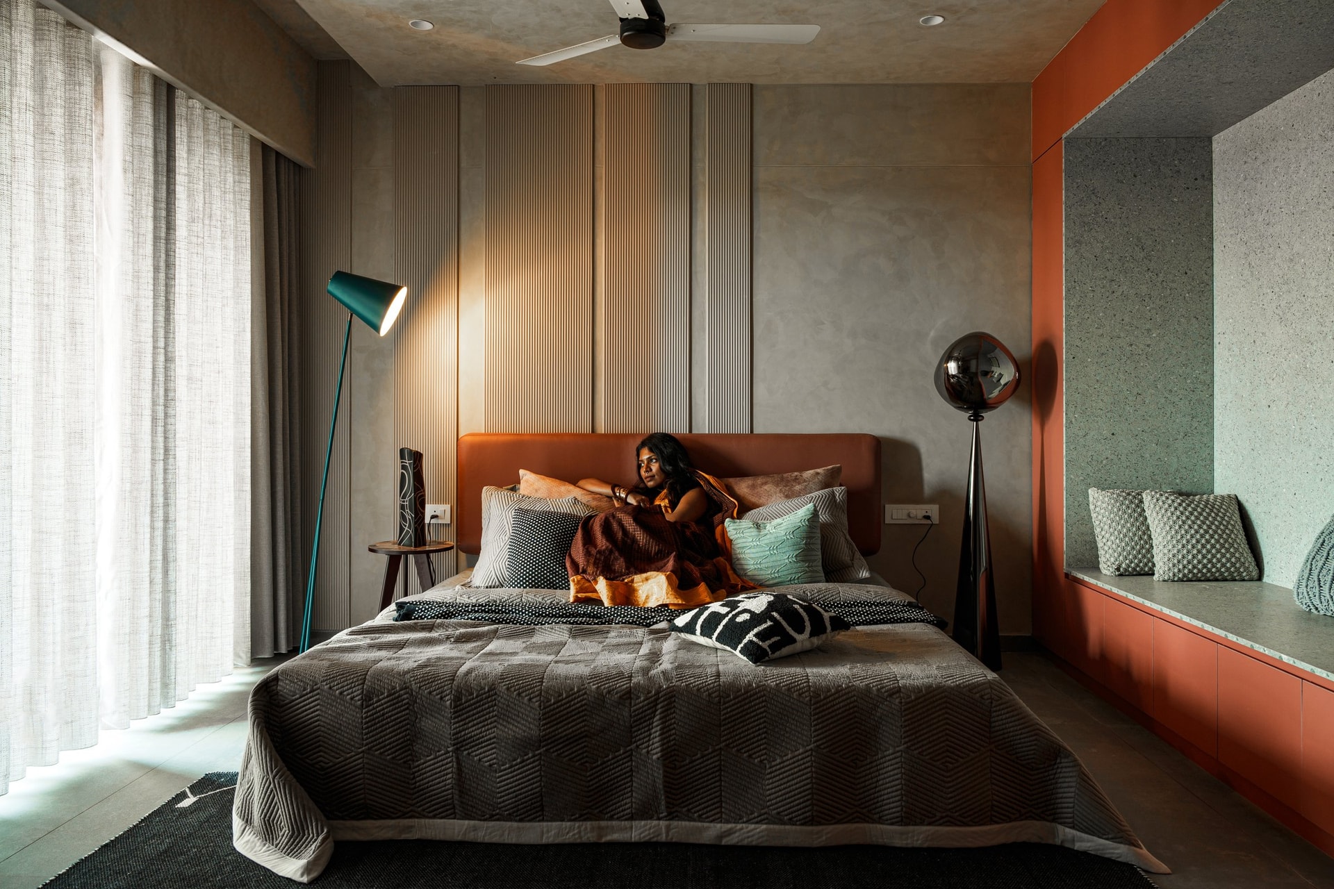 The master bedroom, where a terracotta leather headboard grounds a wall of vertically grooved panelling in muted neutrals