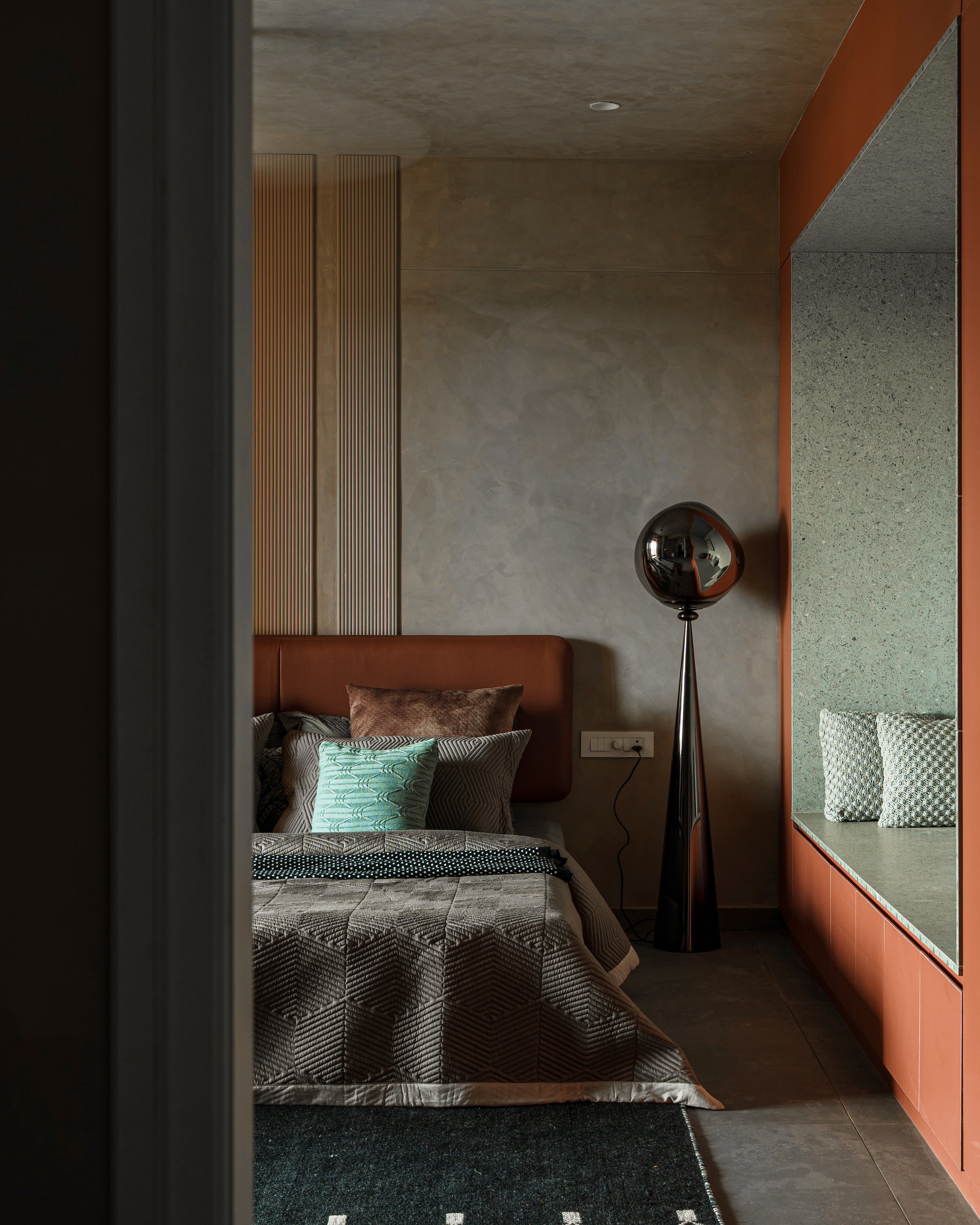 Seen from the doorway, the terracotta-framed window seat turns storage into an architectural gesture
