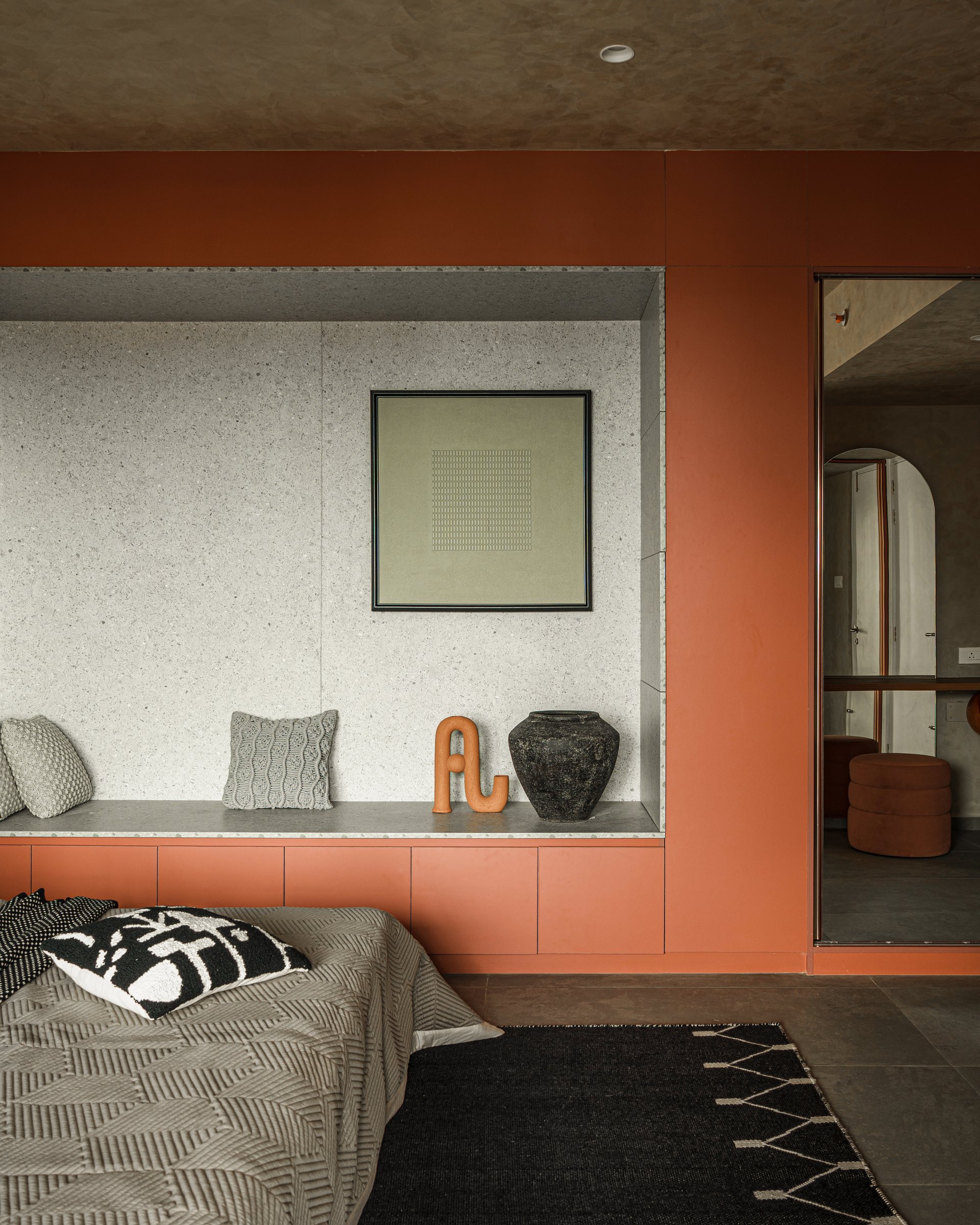 A closer view of the recessed niche, its terrazzo-look stone lining holding a small framed artwork and a pair of sculptural objects