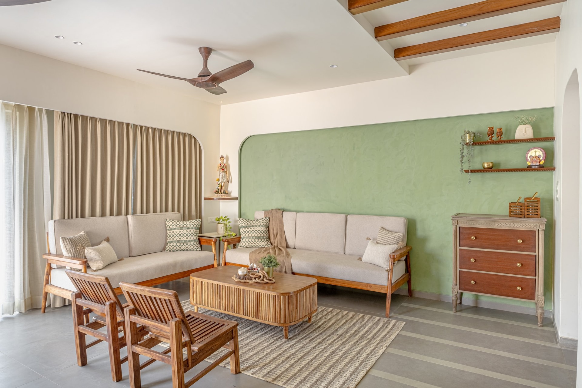 The living room, anchored by a hand-plastered sage feature wall and a fluted wooden coffee table