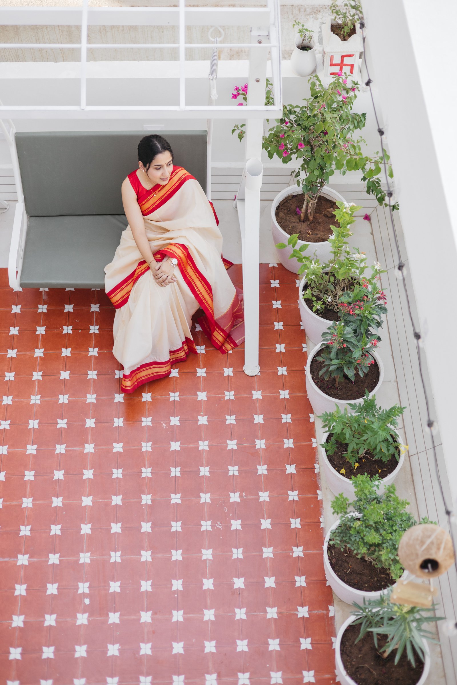 The terrace, finished in patterned red-and-white cement tile and lined with flowering planters