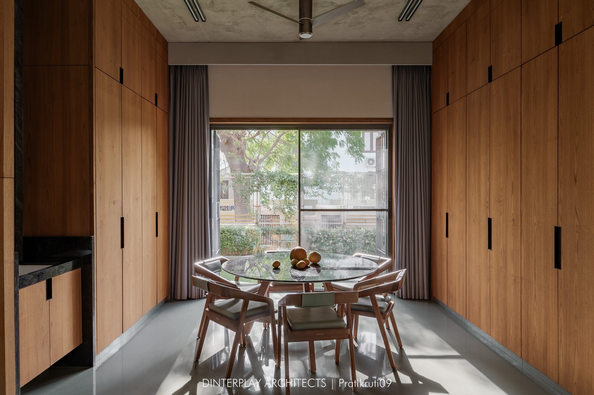 The dining area, lined with floor-to-ceiling timber wardrobes and oriented towards the tree canopy