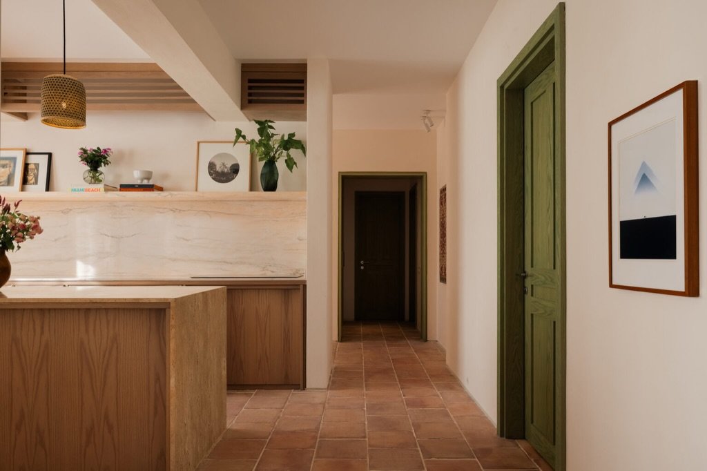 A terracotta-floored corridor frames a green door, the recurring gesture drawn from traditional Egyptian homes.