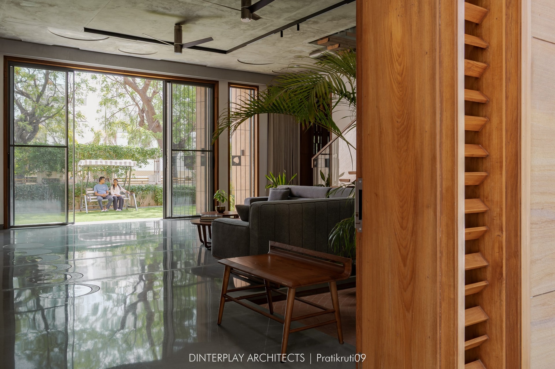 The living volume opens to the garden through a large sliding-glass opening, with a sculpted timber pivot door at the threshold
