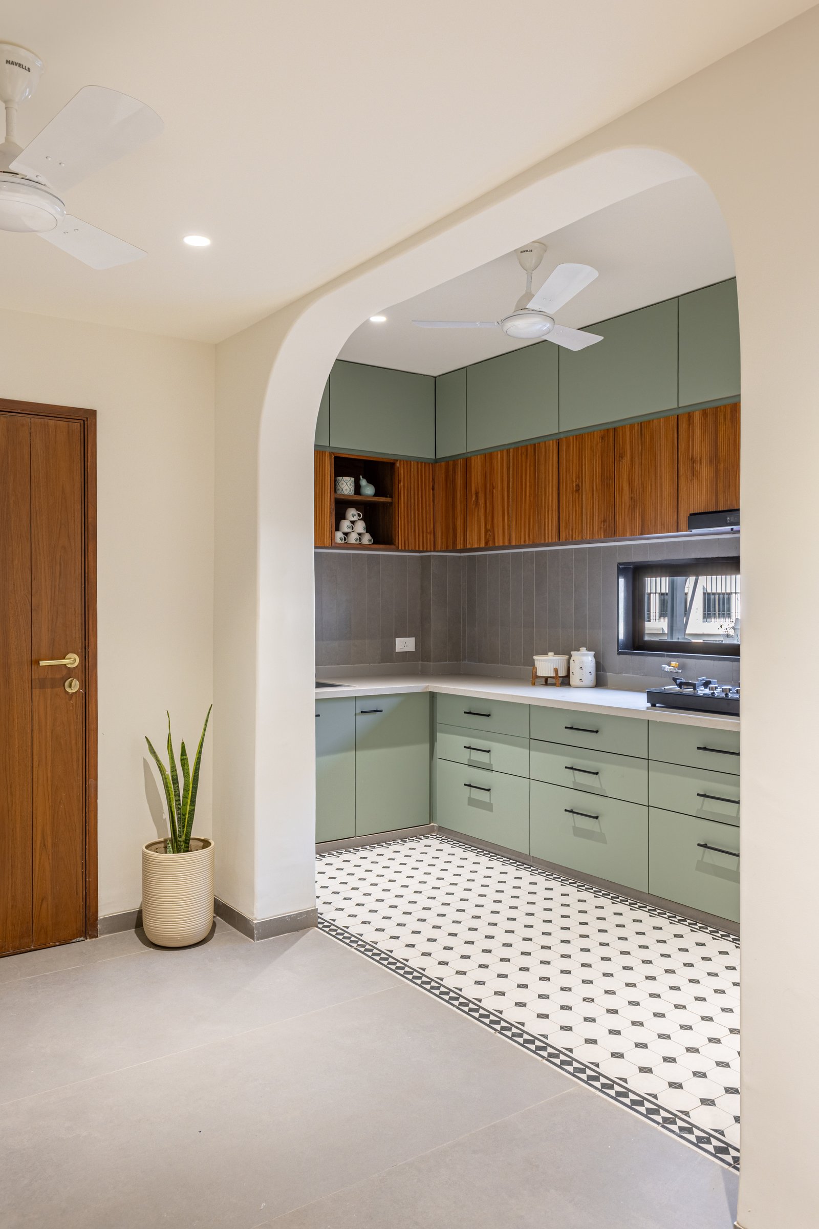 The kitchen, unlocked by the staircase relocation and finished in muted sage cabinetry with a patterned monochrome floor