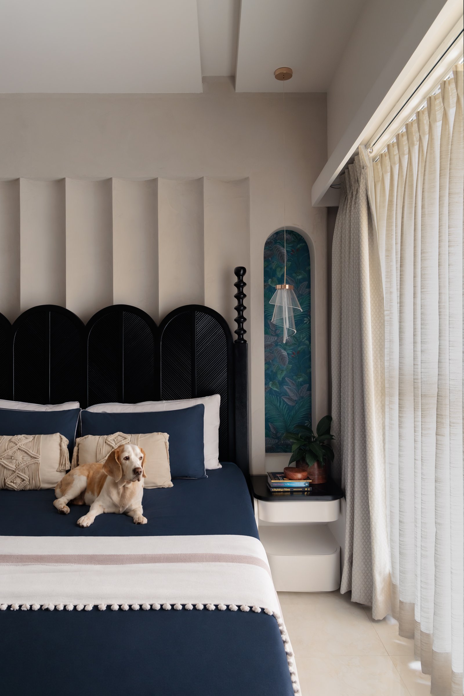 Navy bedding and a botanical wallpaper niche compose the bedroom's quieter register