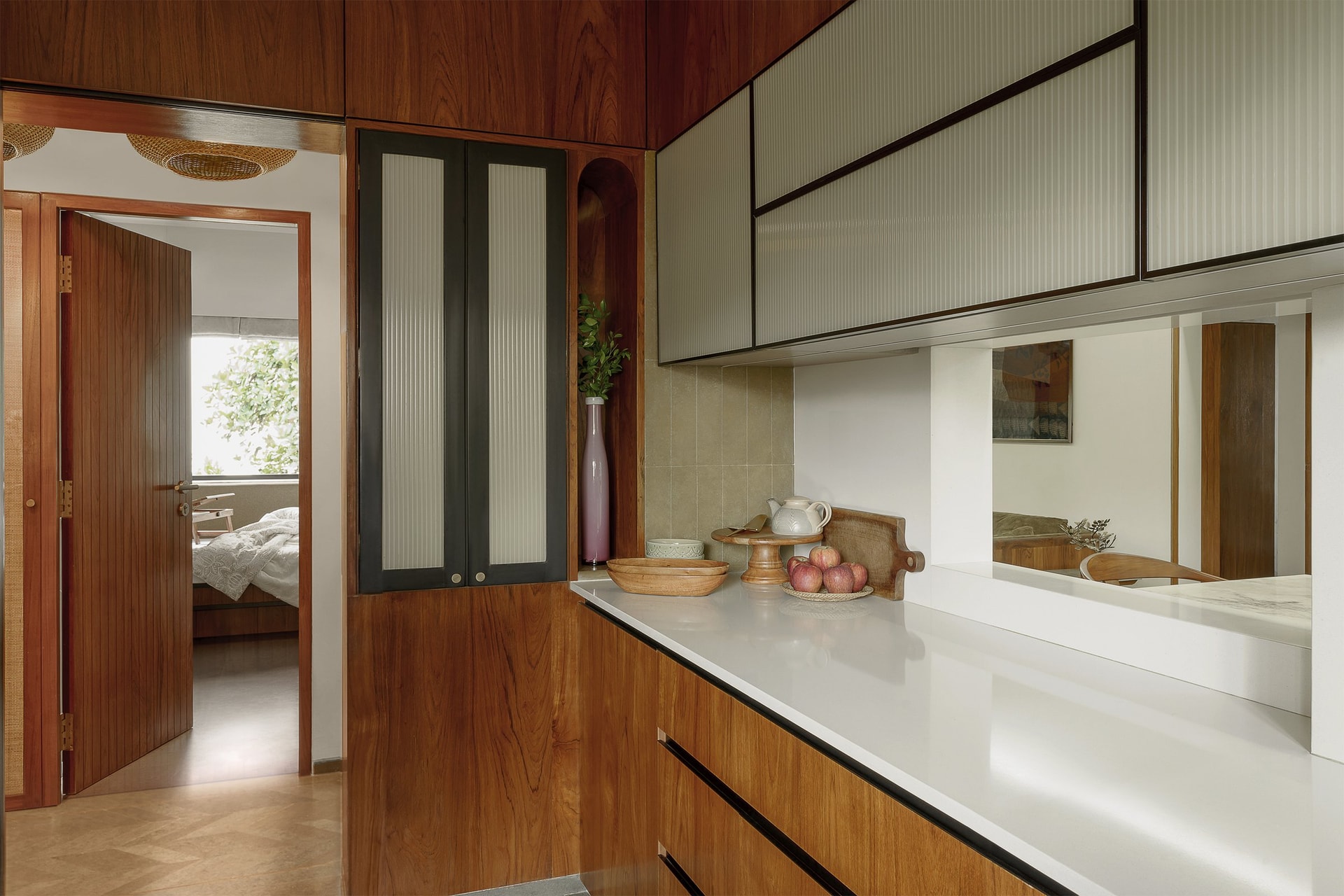 The compact kitchen, its reeded glass upper cabinets opening through a service window onto the dining beyond