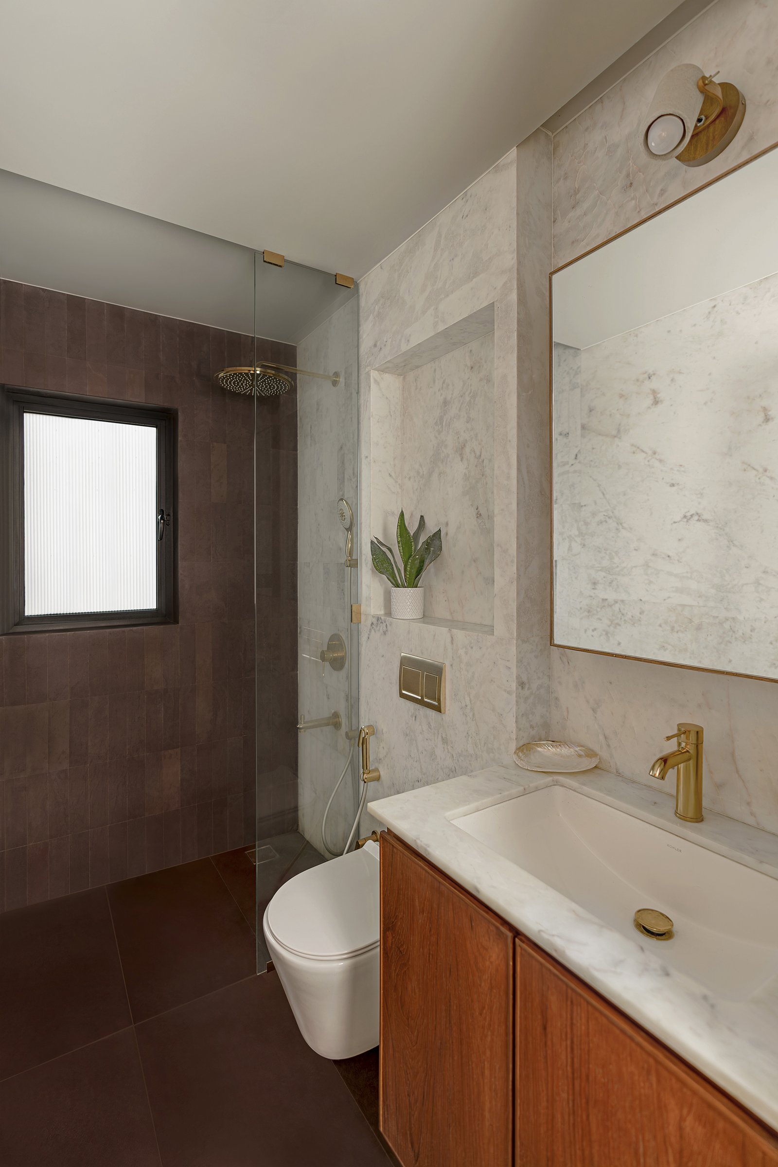 The primary bathroom, where tobacco-toned tile meets veined marble and warm brass fittings