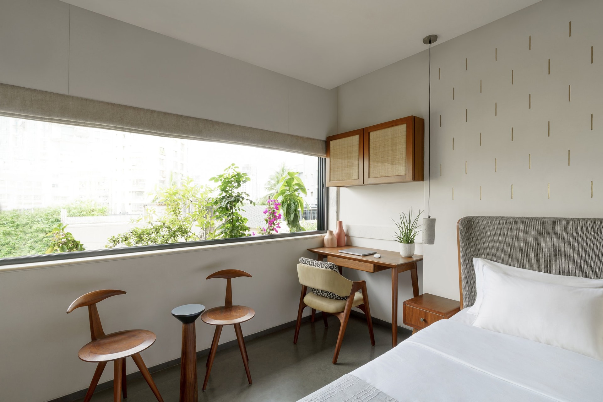 The desk-and-window corner of the primary bedroom, with a cane-fronted cabinet floating above