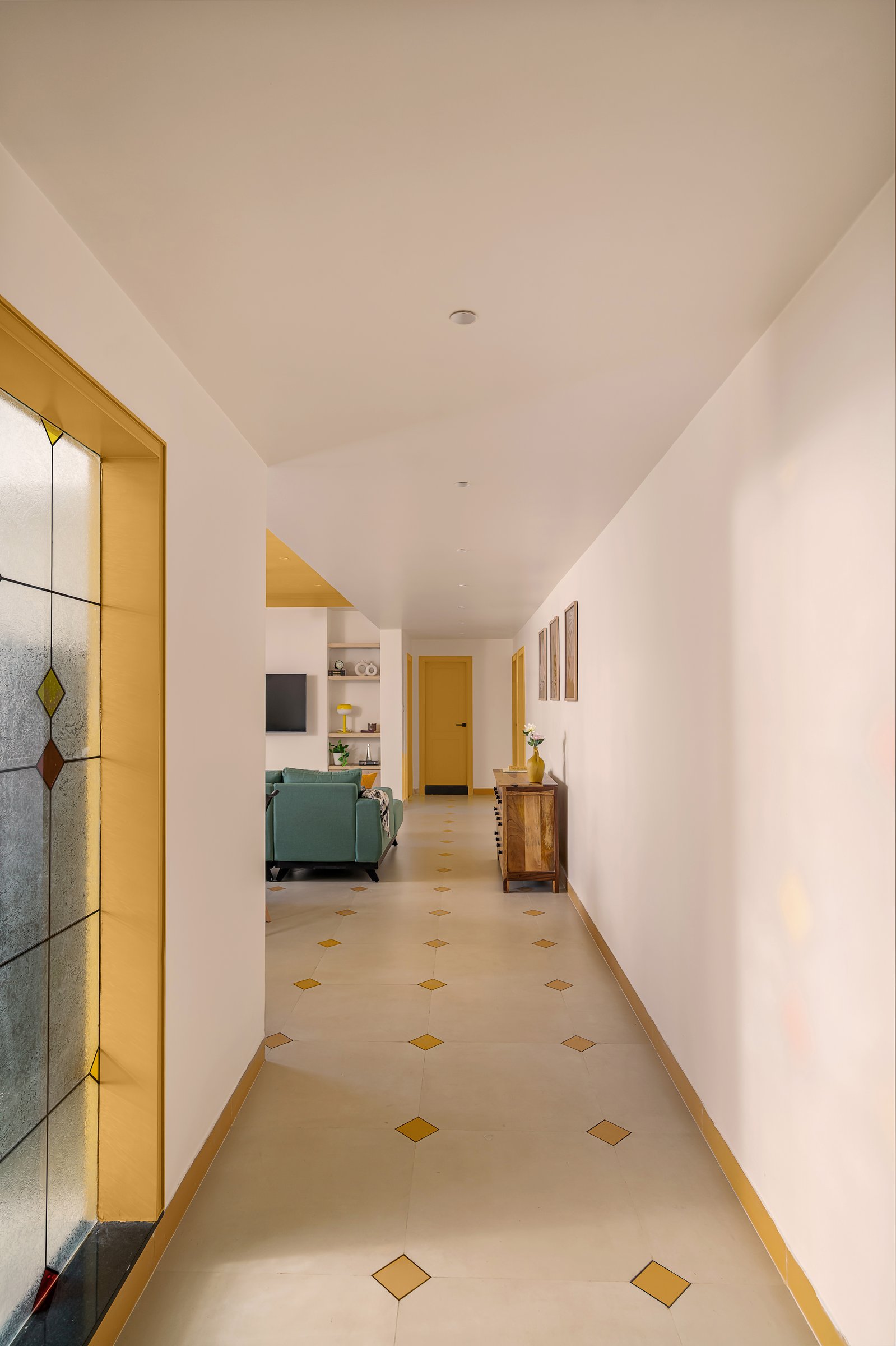 The entry corridor, where a diamond-inlaid floor and a stained-glass panel in yellow establish the apartment's material language before any room announces itself