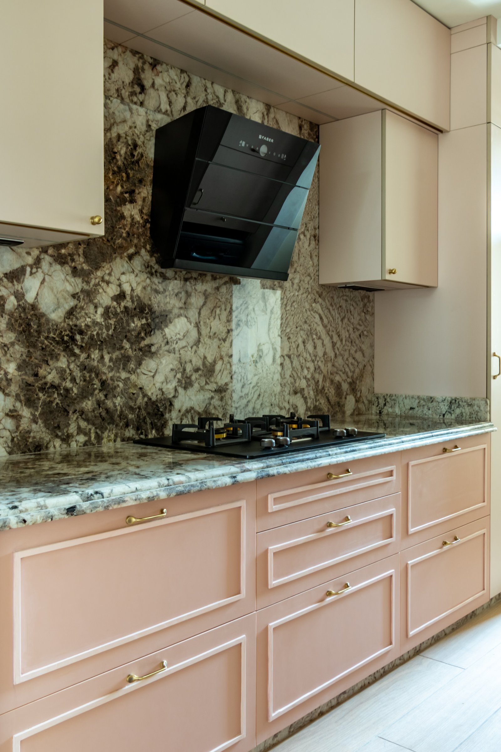 The kitchen, where imported quartzite in dark veining holds attention above blush cabinetry