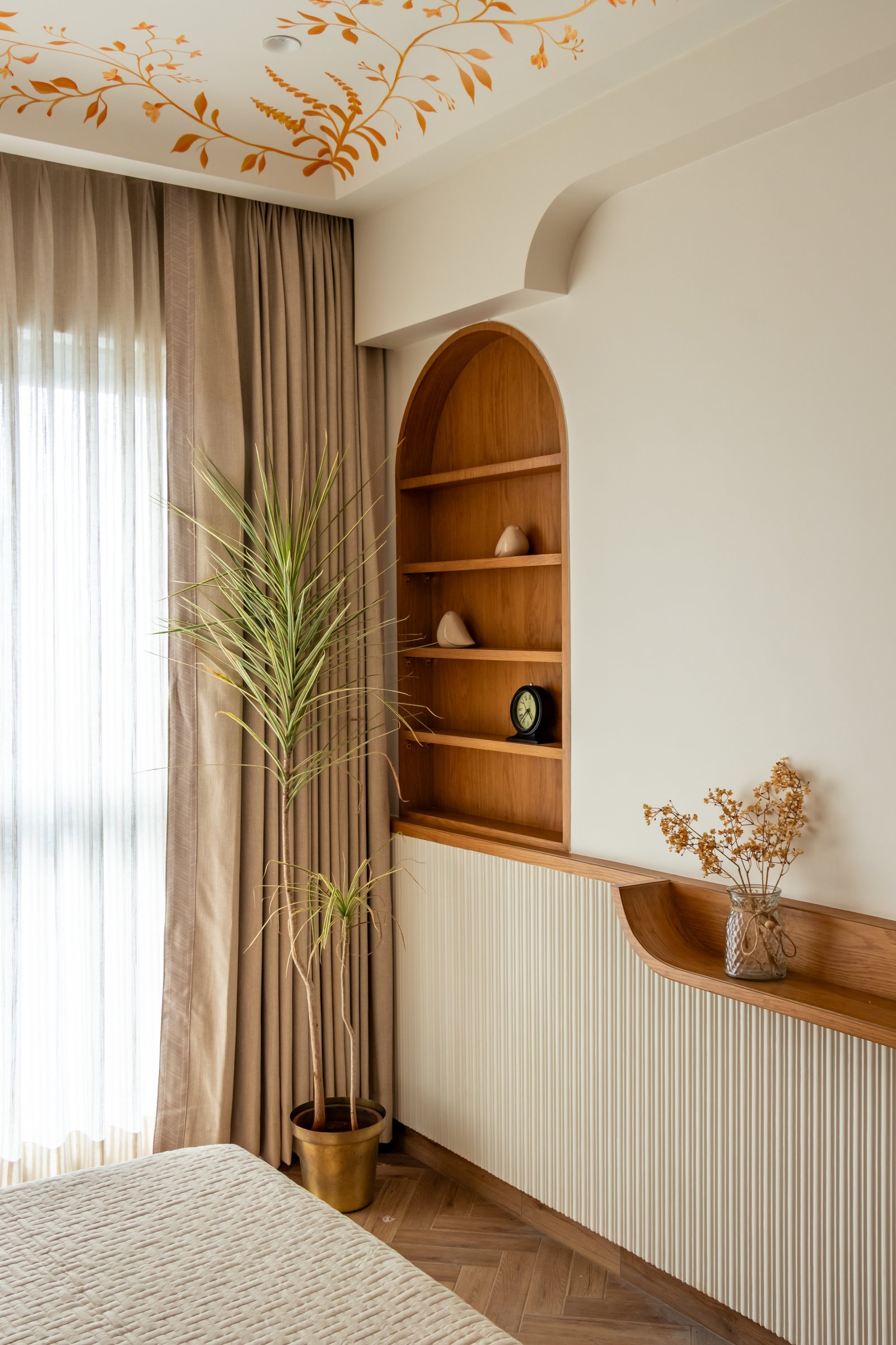An arched niche and fluted console beside the bed, echoing the arched openings elsewhere in the home