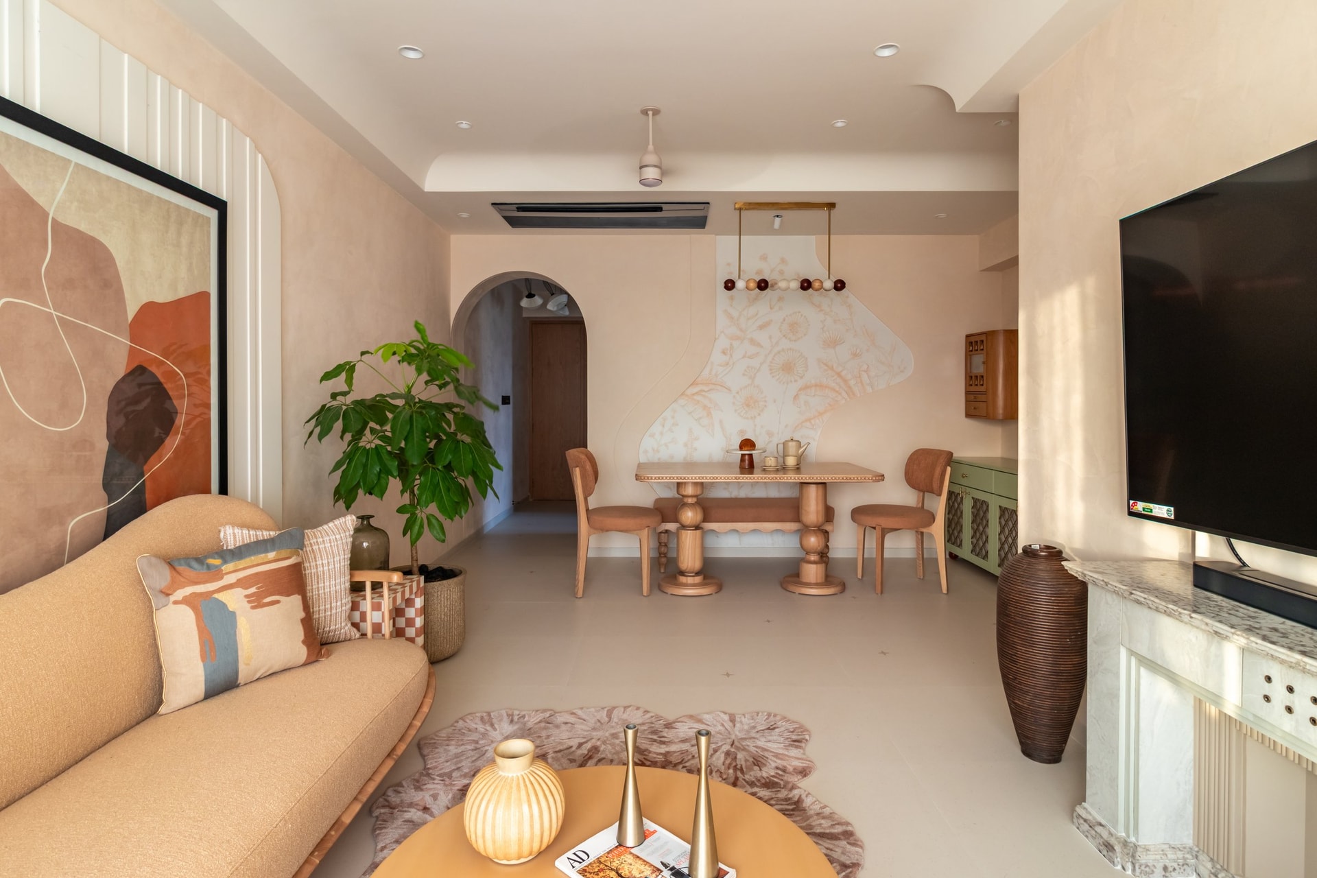The living and dining volumes share a single continuous space, resolved in warm sand-toned plaster and low horizontal surfaces