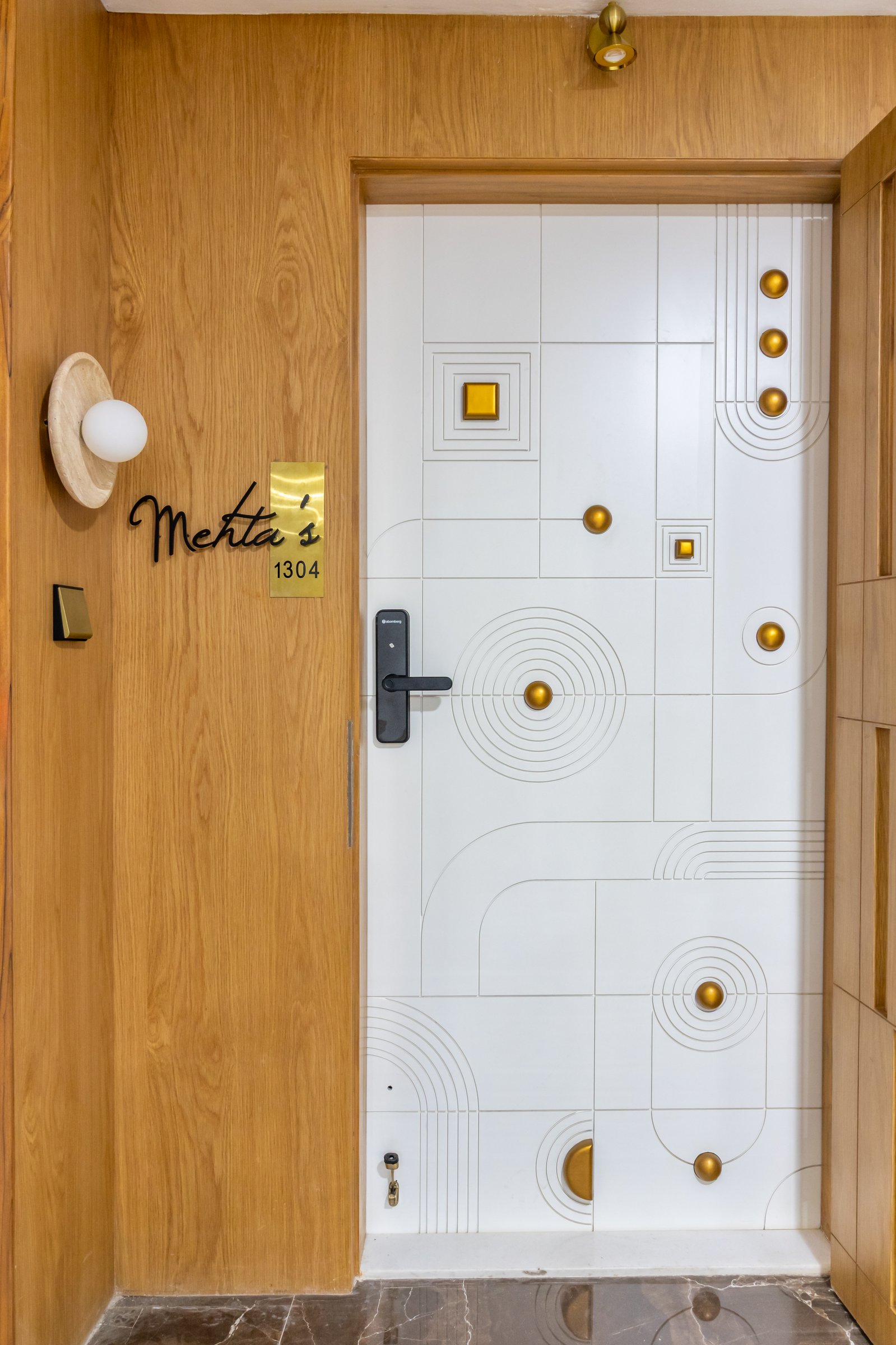 The entrance door, its incised lines and small brass discs setting a tone of quiet handcraft before the home begins