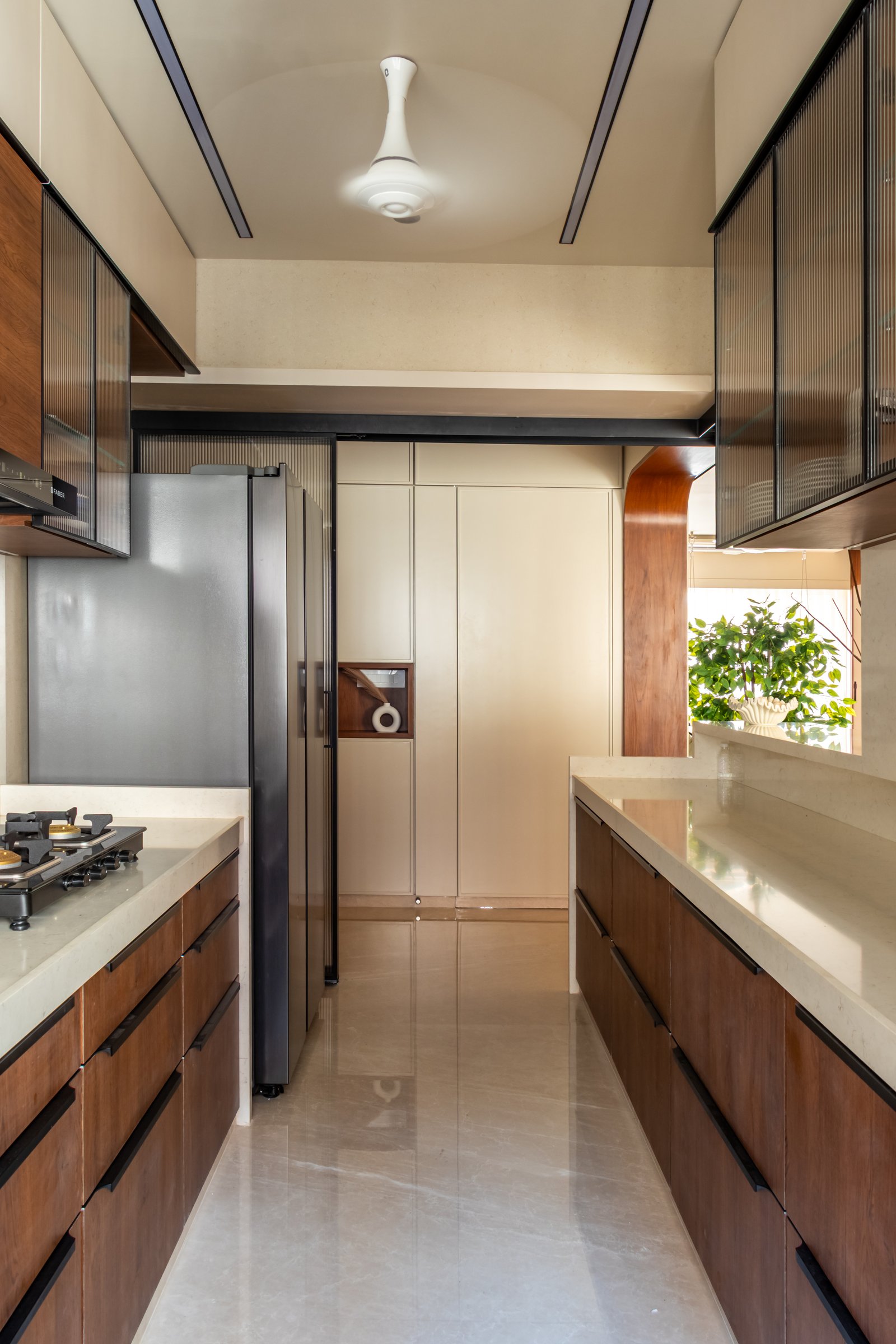 The galley kitchen, with parallel counters and warm walnut cabinetry running beneath reeded-glass uppers