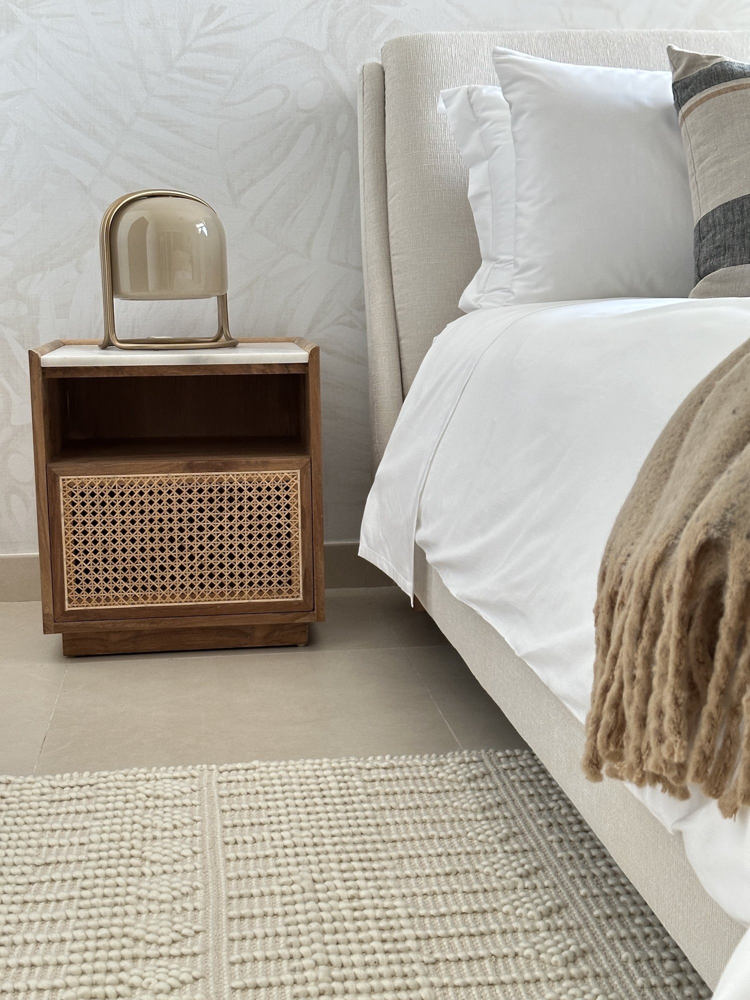 A closer look at the bedside composition: cane, marble, and warm timber meeting in a single considered piece