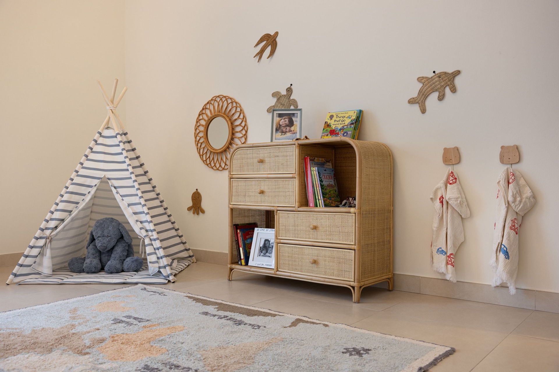 The play corner, with its striped canvas teepee and rattan storage chest set against small woven animal silhouettes on the wall