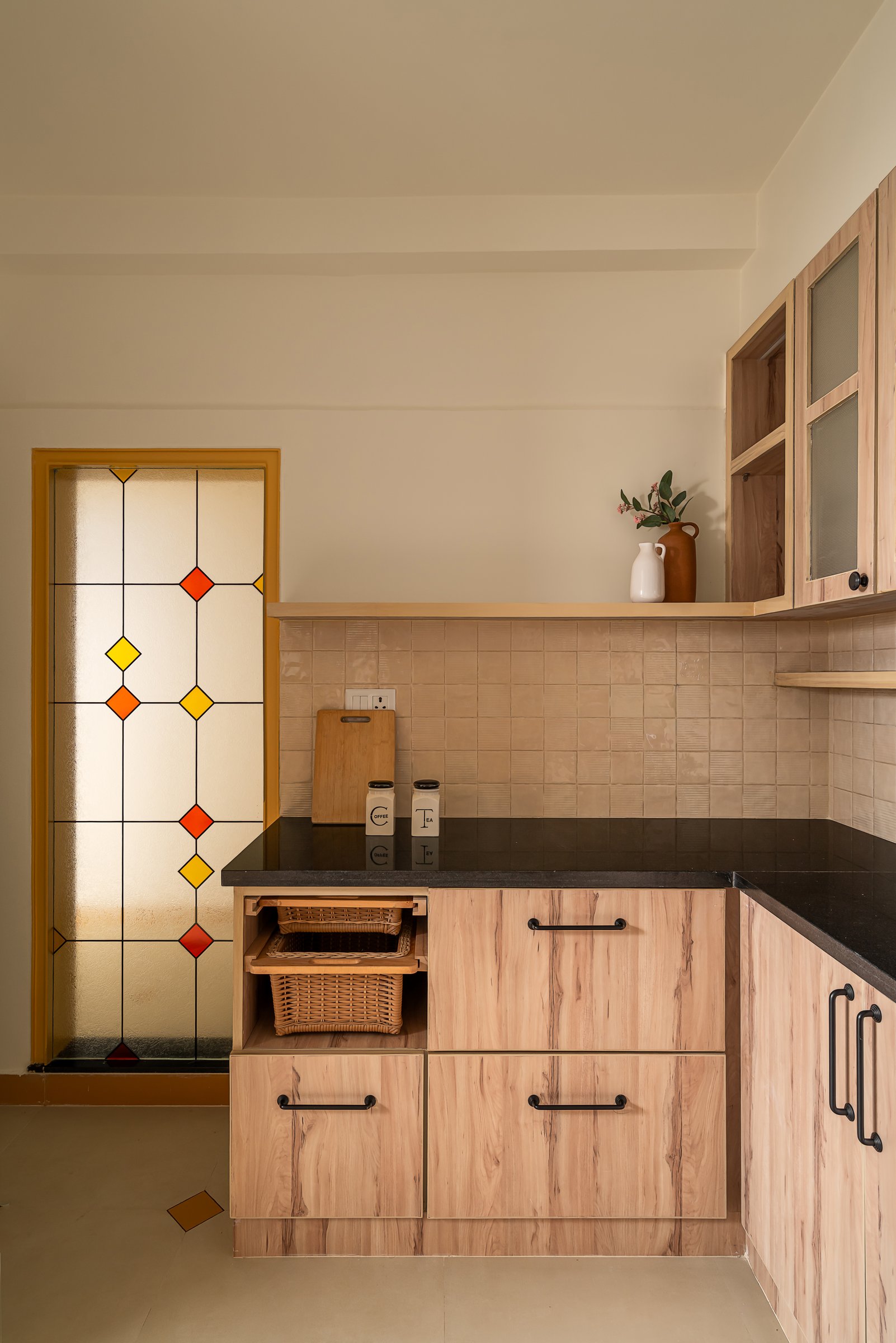 A stained-glass panel set into an ochre-framed opening translates the diamond floor motif into a different medium