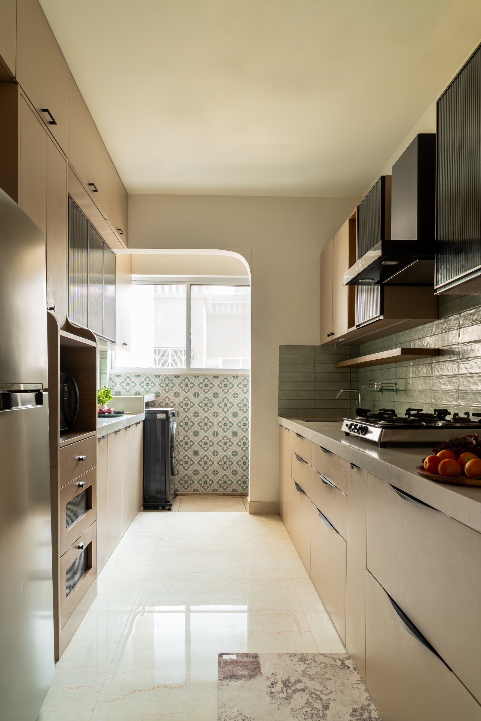 The parallel kitchen, with blush cabinetry, a soft green backsplash and fluted dark upper units above the hob