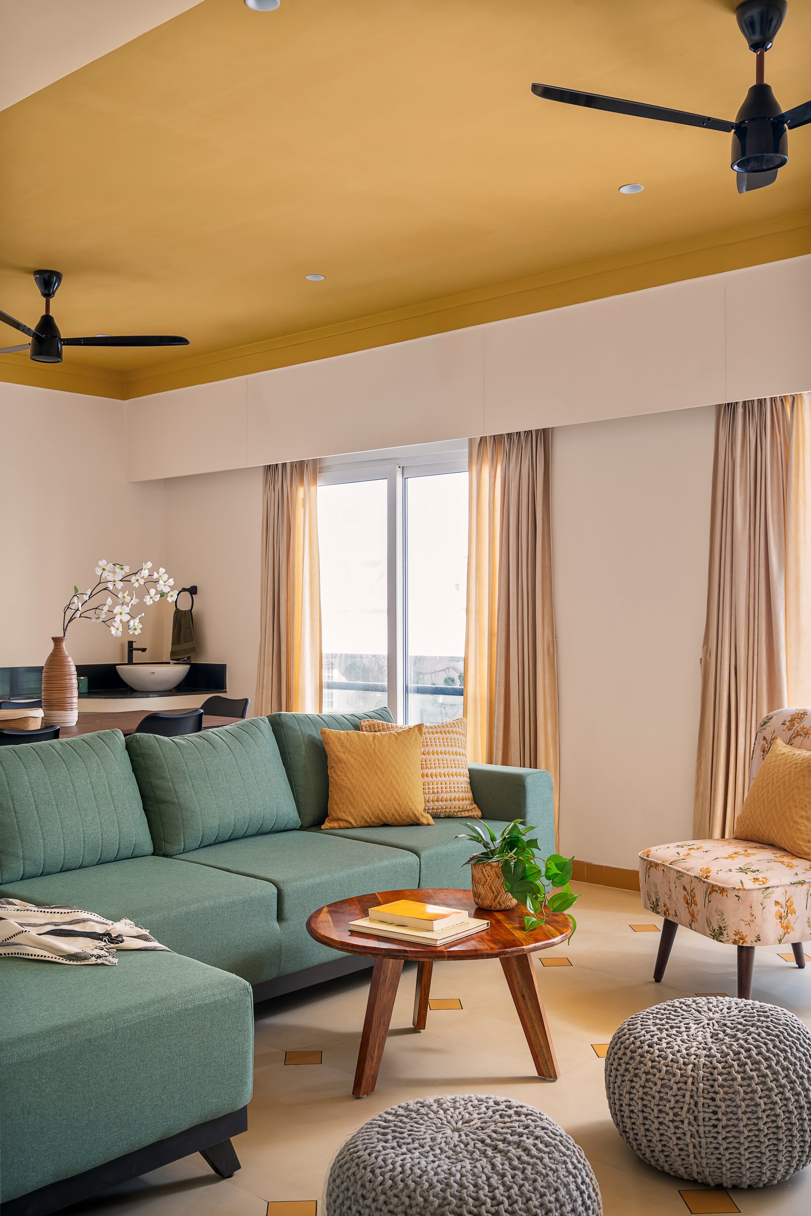 A view across the sectional to the ochre ceiling and the round wooden coffee table with its tripod base
