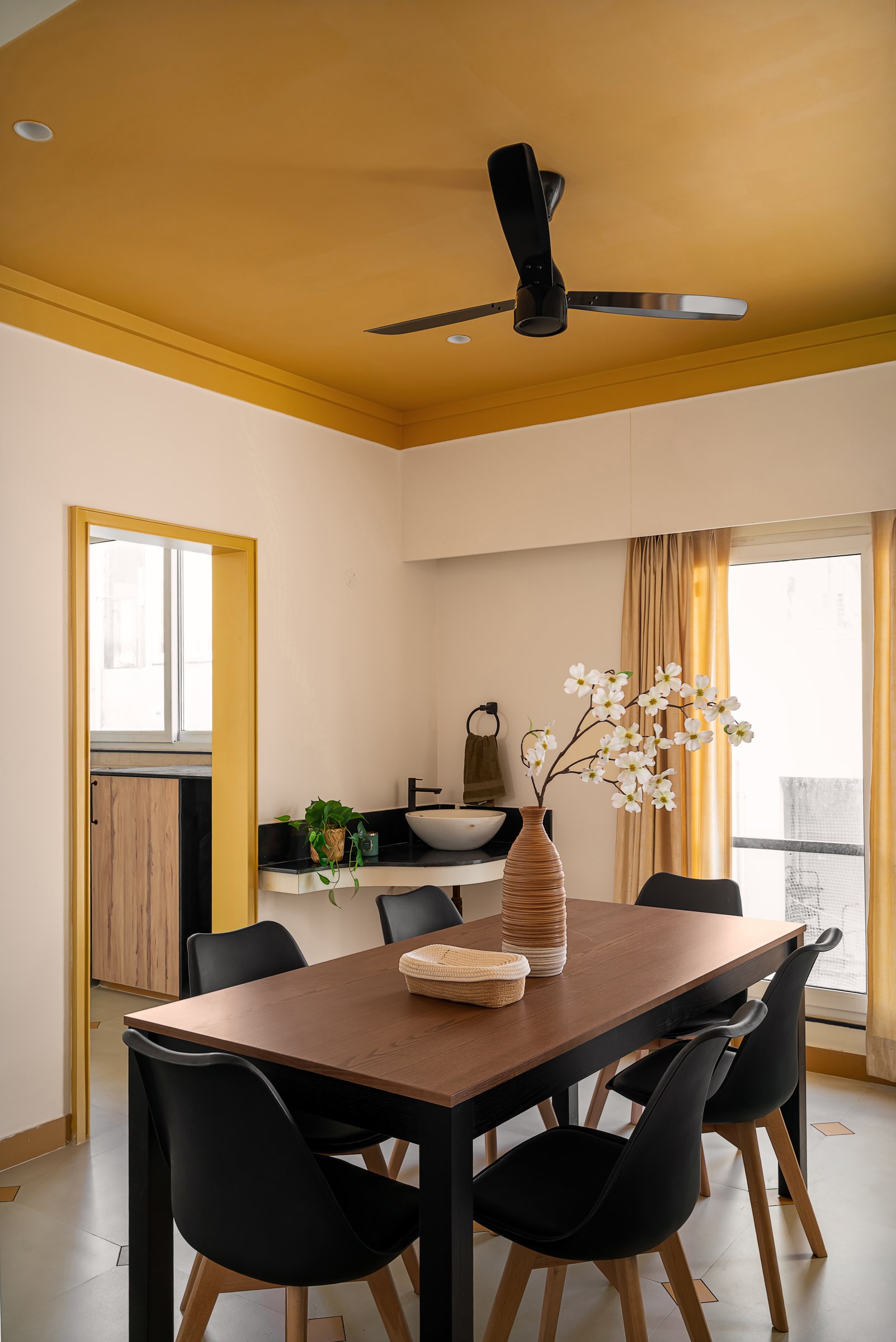 The dining area, framed by the extending ochre ceiling and a black stone service console