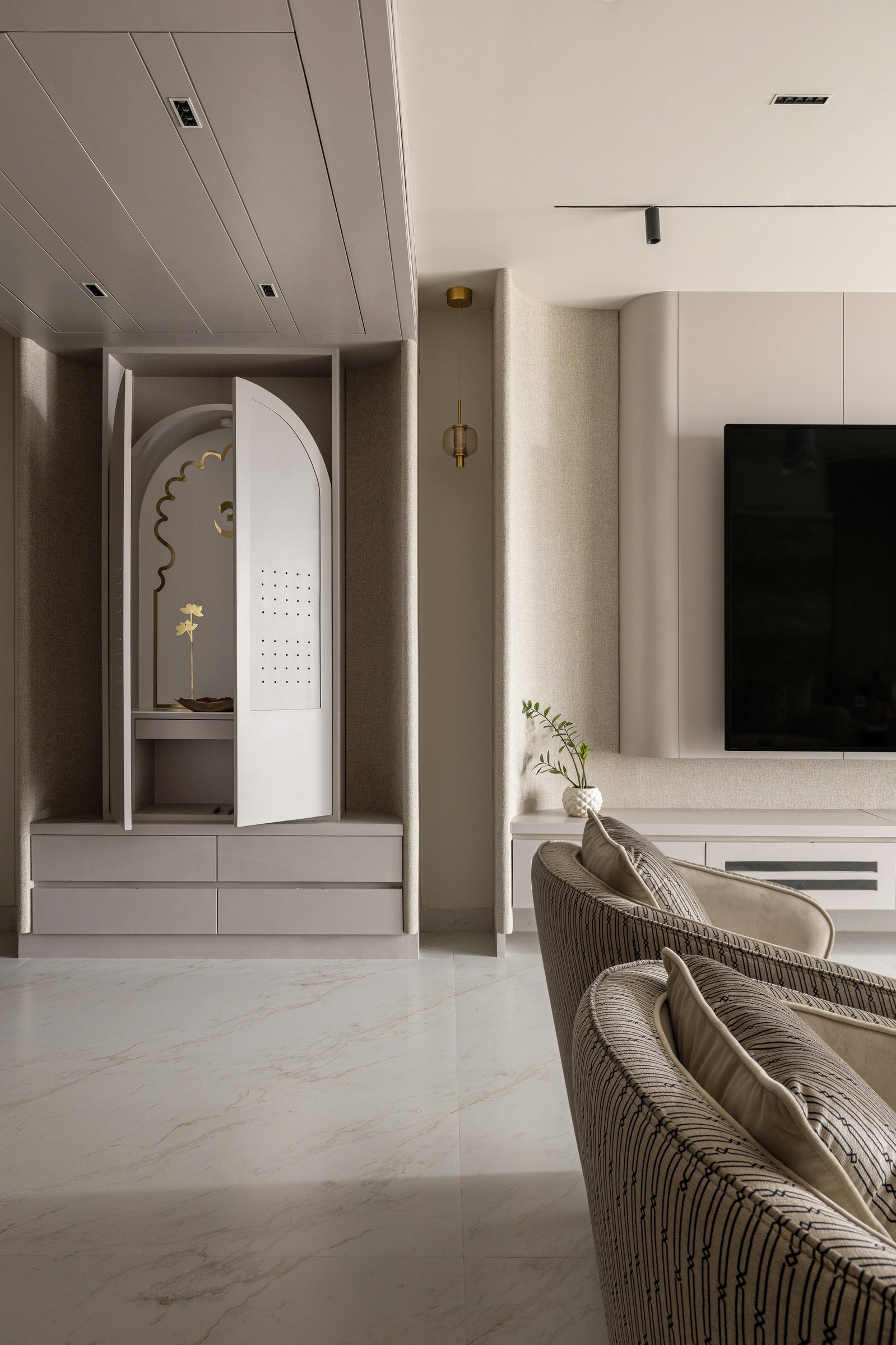 The puja enclosure, an arched cabinet set into a fabric-clad recess and marked by a small warm-toned pendant