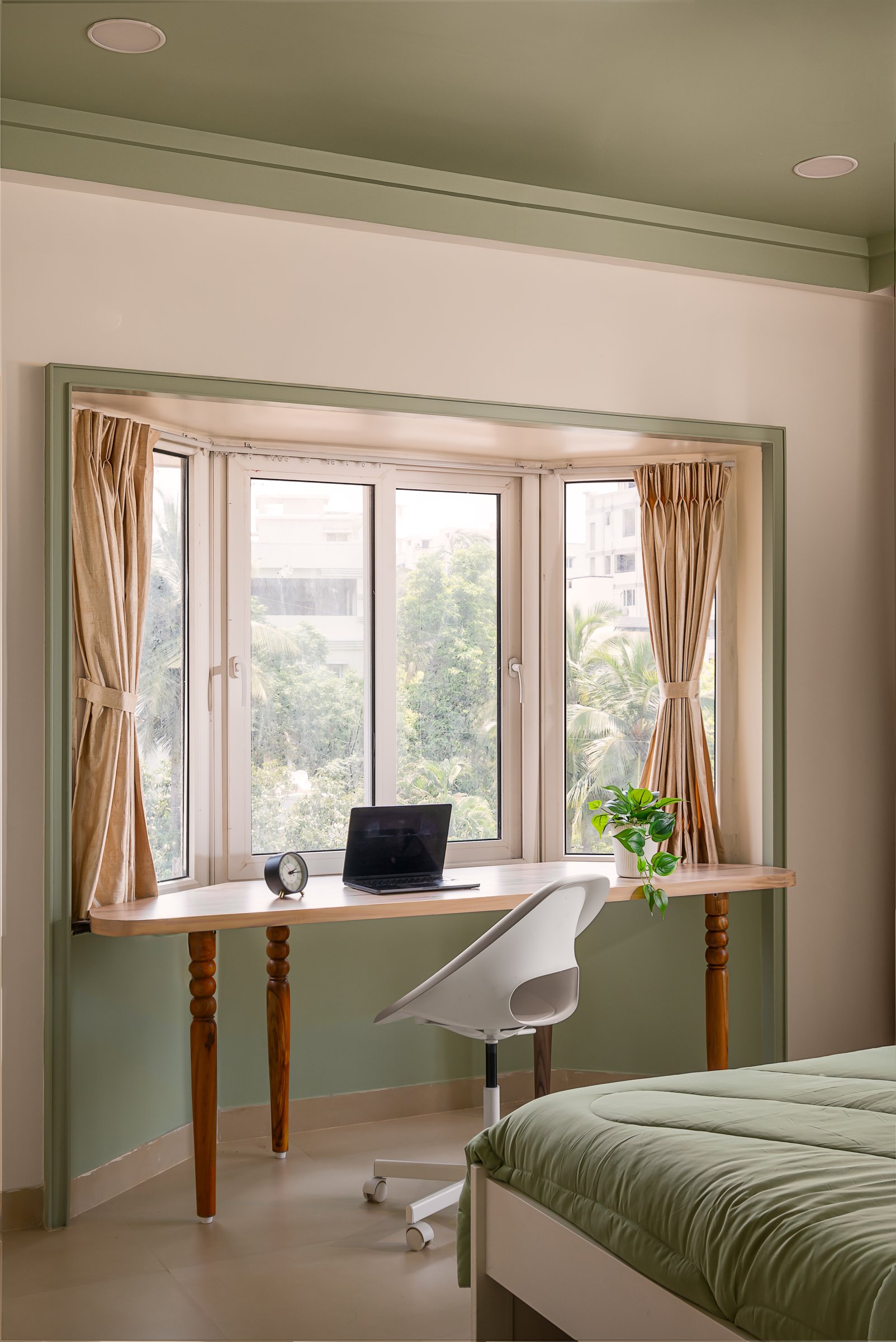 A slender desk fitted into the master bedroom's window bay, extending across the sill on turned wooden legs