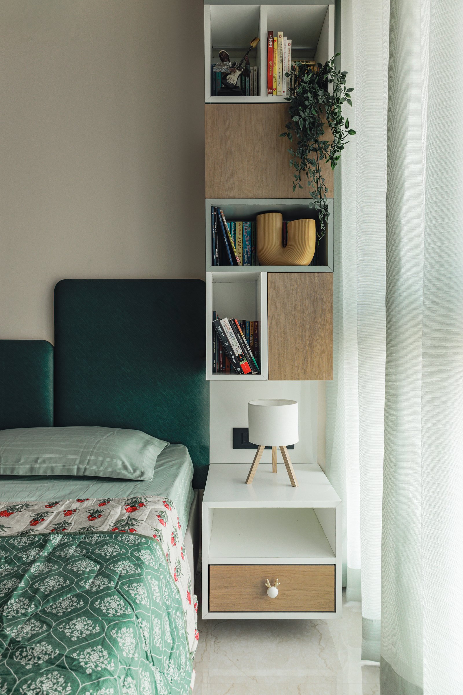 A vertical column of open and closed compartments beside the bed, where storage becomes architectural