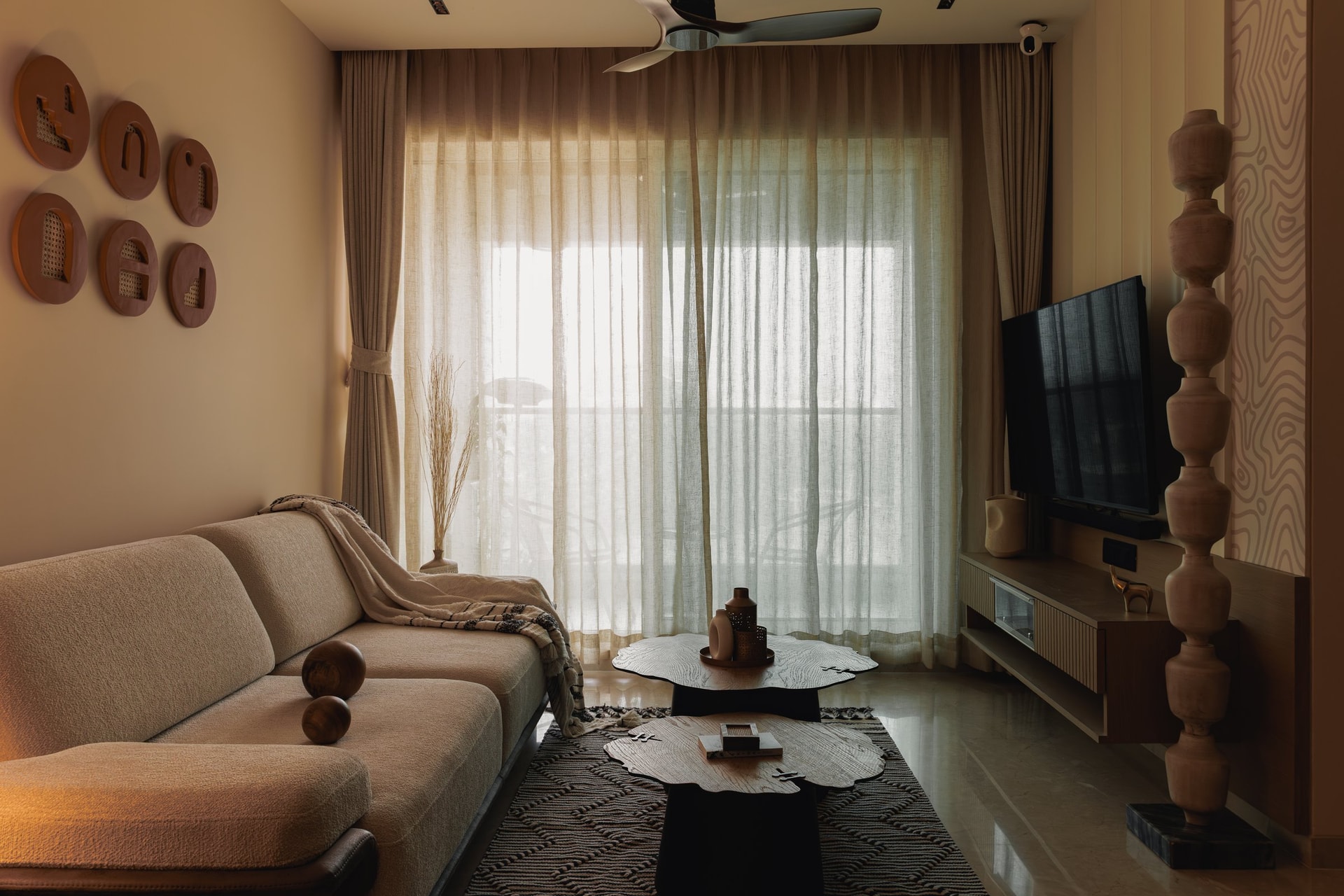 The living room, organised around a bouclé sofa and a pair of organic-edged timber tables