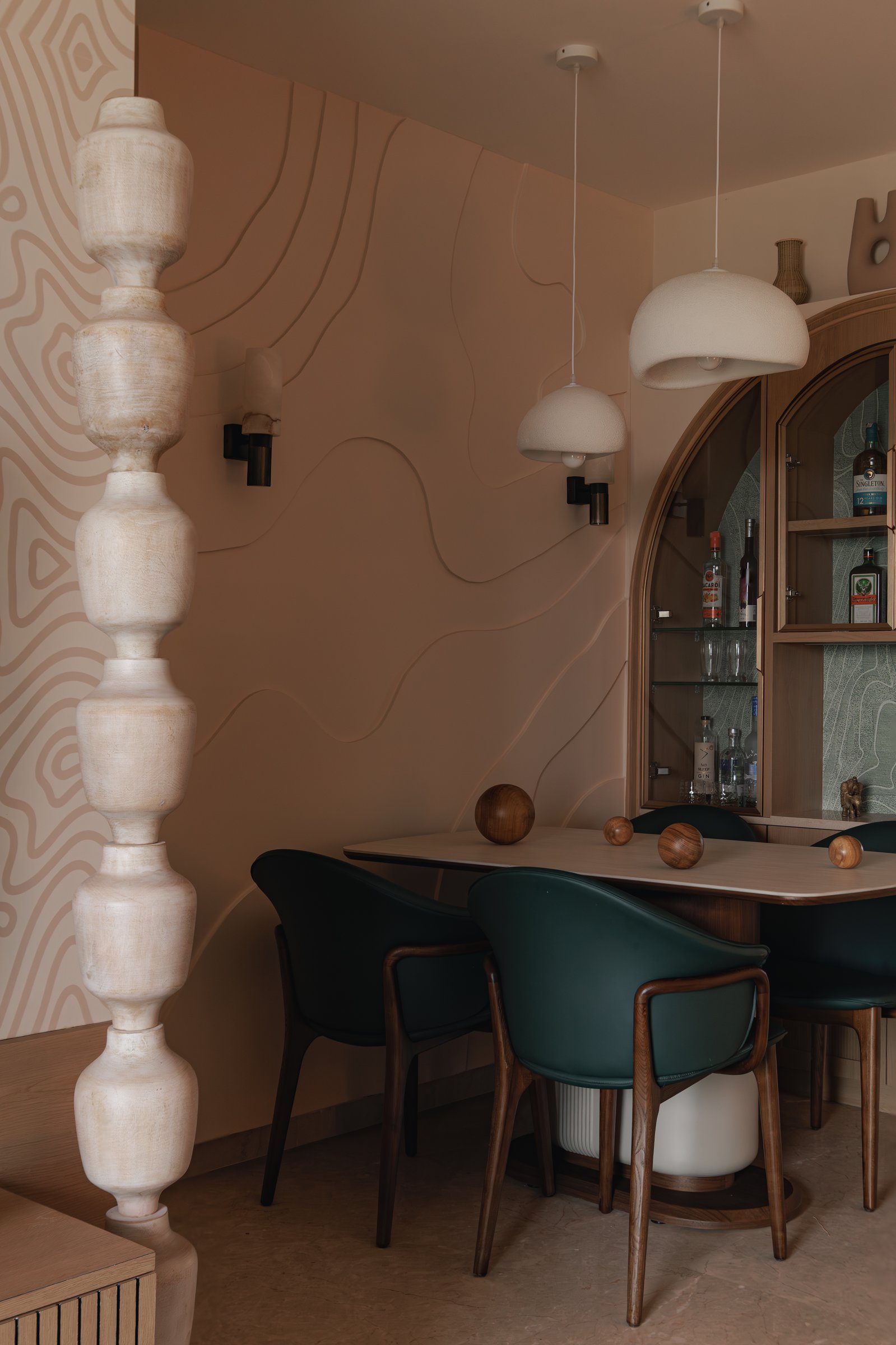The dining area, defined by an undulating relief wall and staggered bouclé pendants