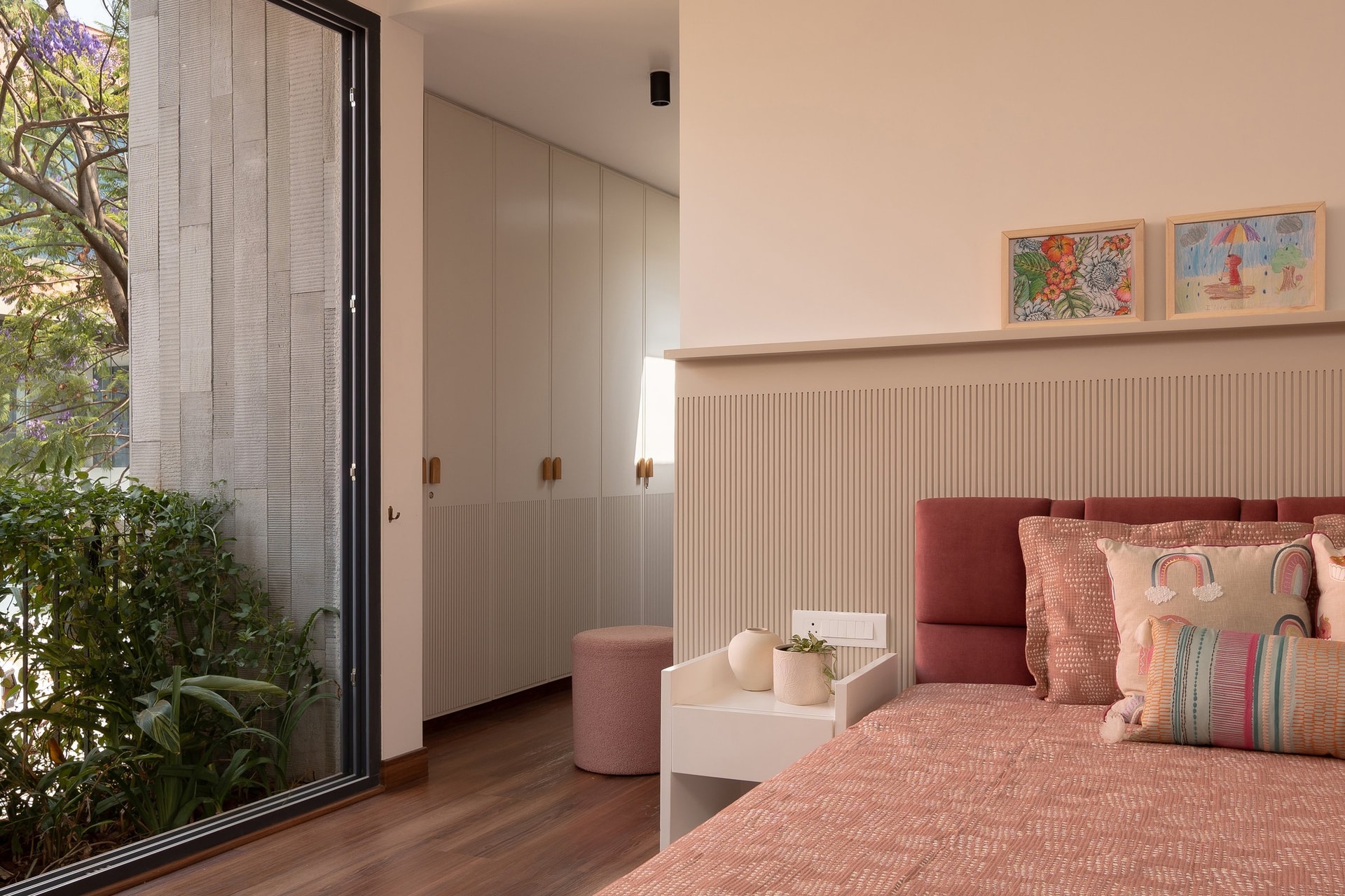 The child’s bedroom, where a fluted panel headboard is layered with a coral upholstered backrest and patterned cushions