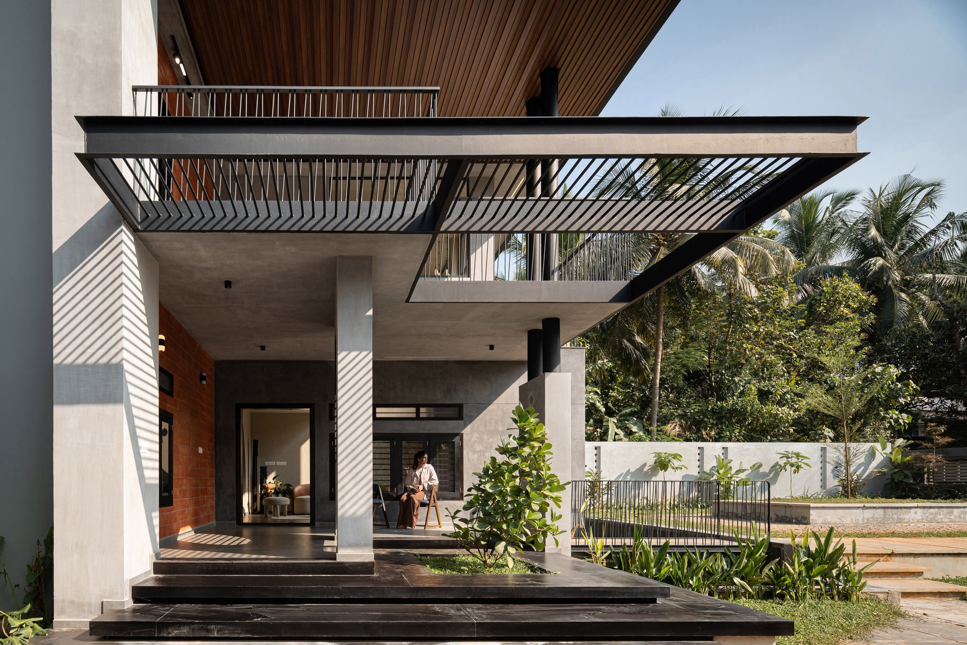 The entrance porch, where a louvred canopy throws a diagonal screen of shadow across the arrival court