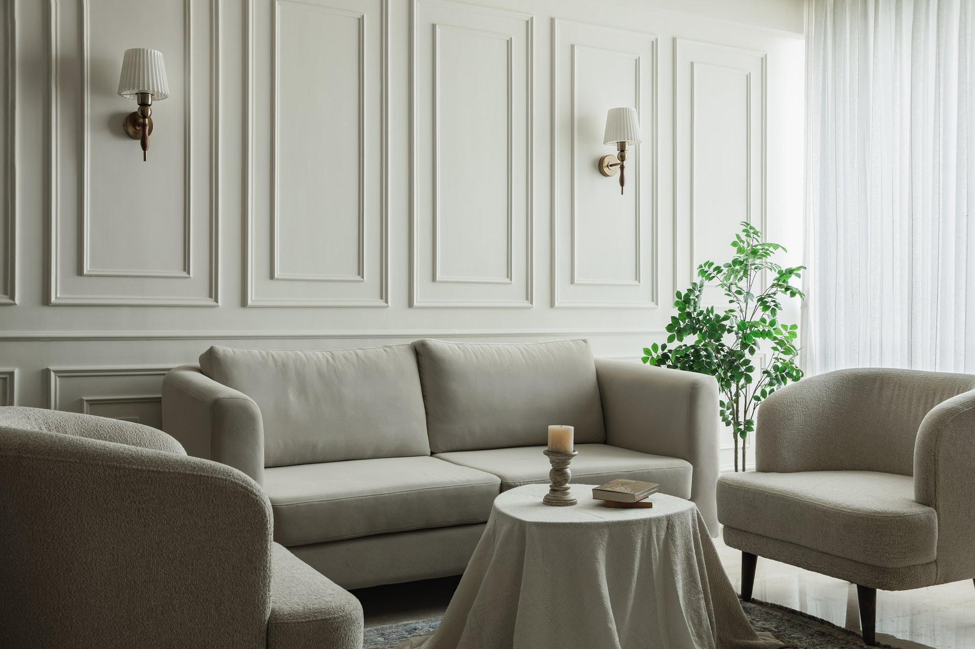 The living room, where ivory panelling and brass sconces frame a palette of soft neutrals and bouclé upholstery