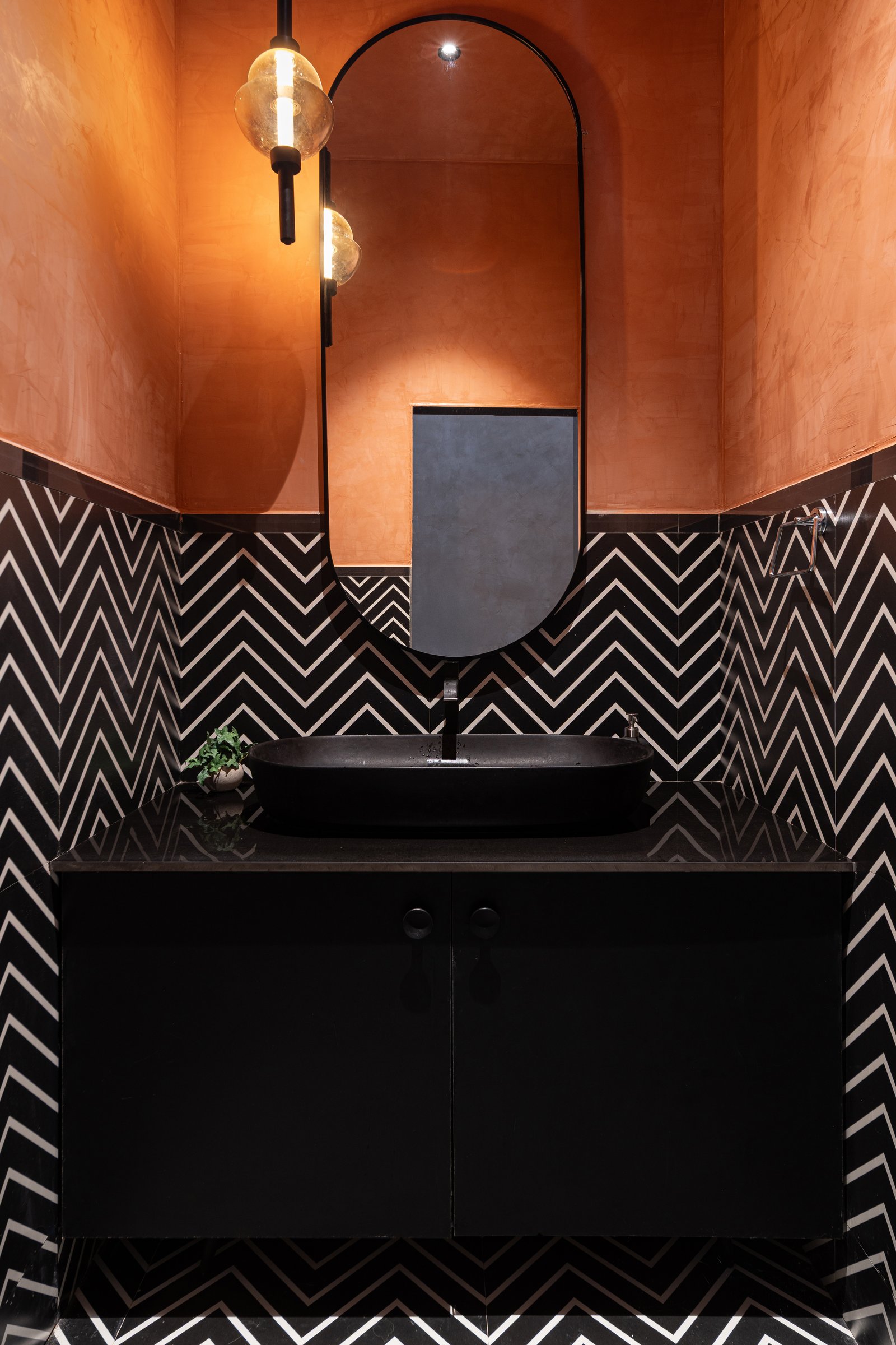The ground-floor wash area, where burnt-sienna lime plaster meets a dado of chevron tile