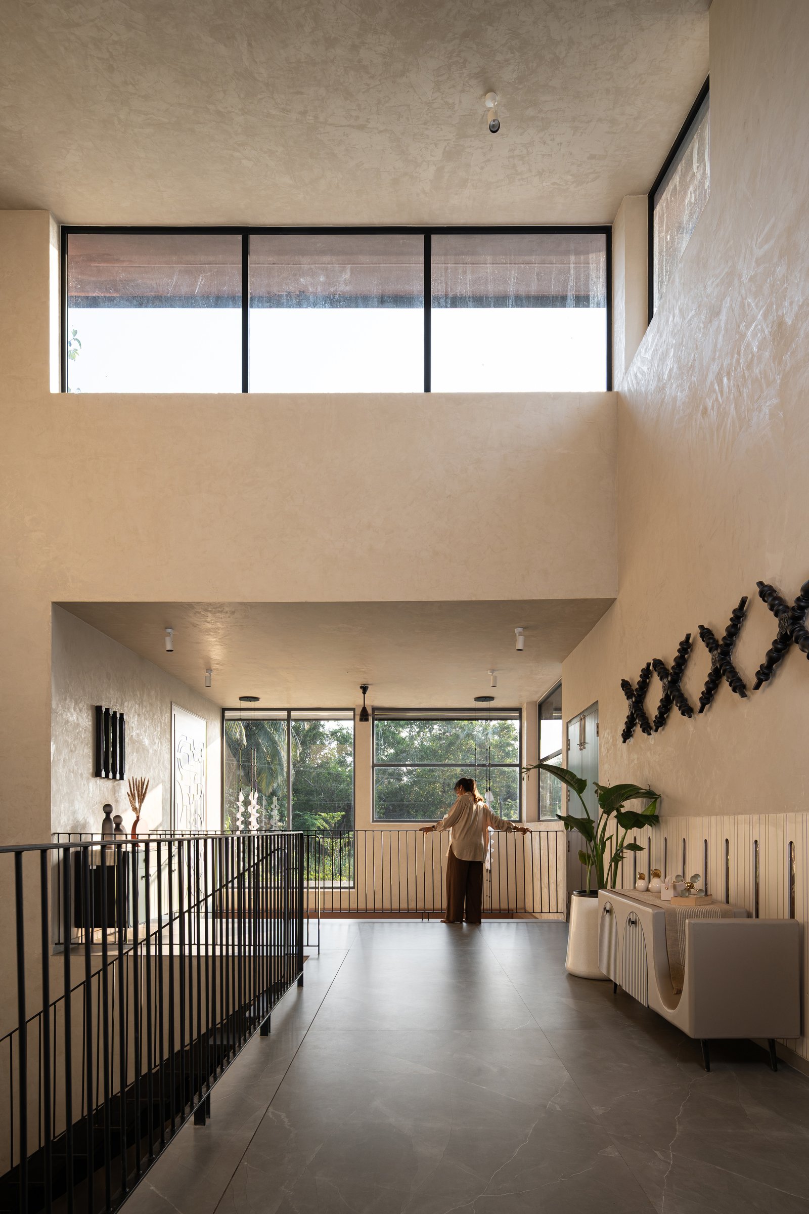 The upper landing, lit by a band of clerestory glazing above a sculptural wall arrangement