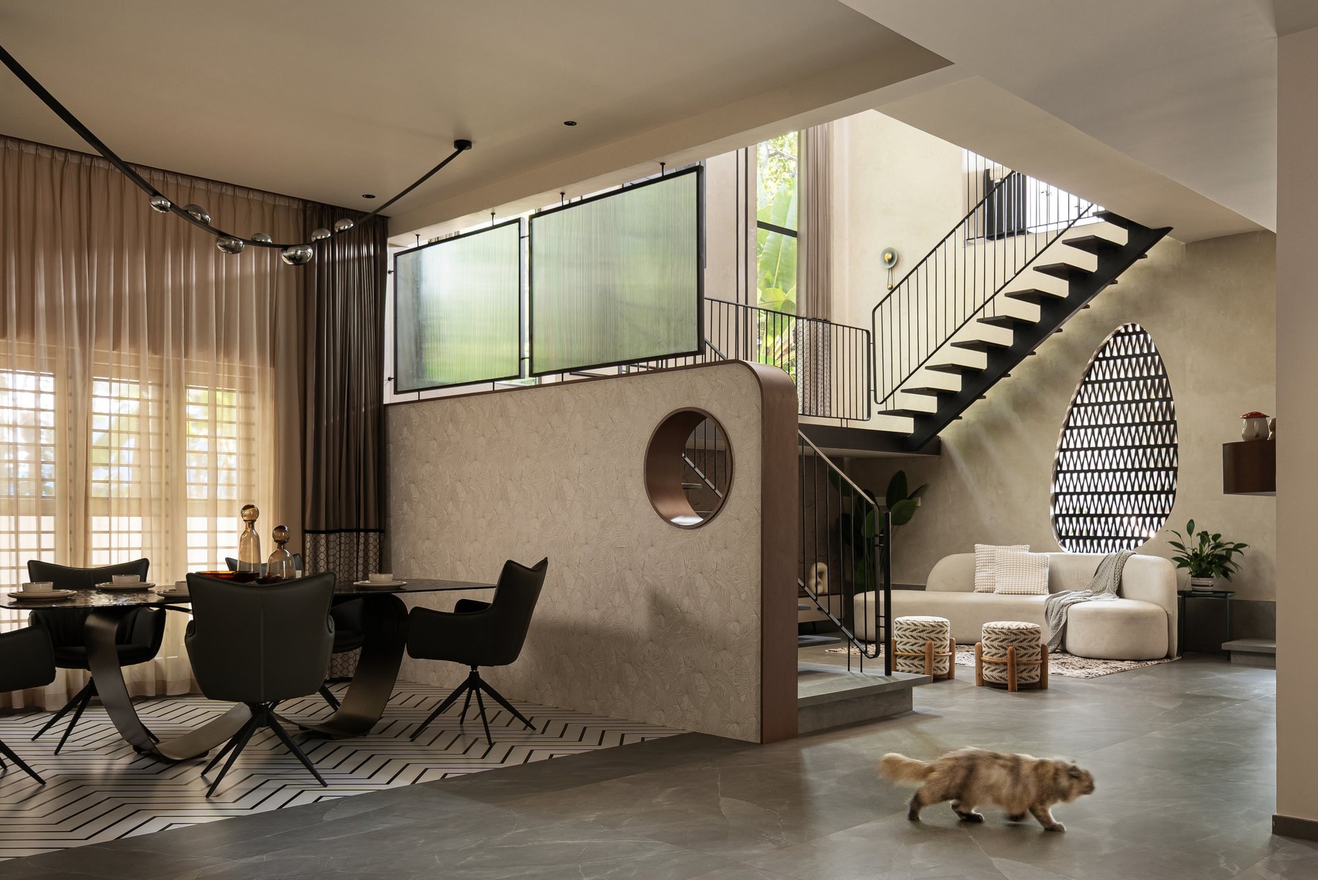 The dining and family living zones share one double-height volume, linked by a chevron floor inlay and a copper-ringed porthole